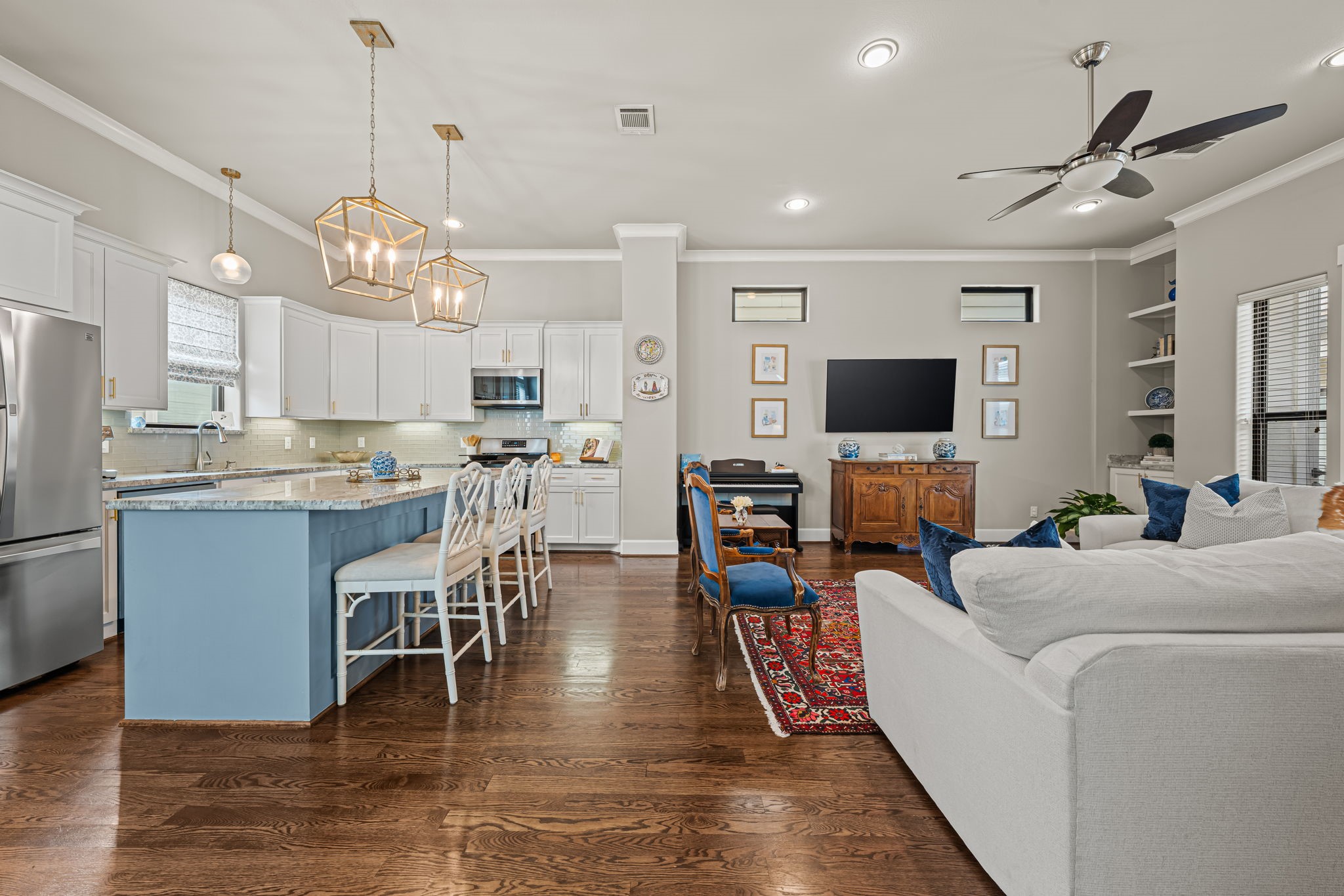 Cooking and gathering share one welcoming space, with the kitchen open to the living room beyond. The arrangement invites long conversations that carry easily from meal preparation into the evening.