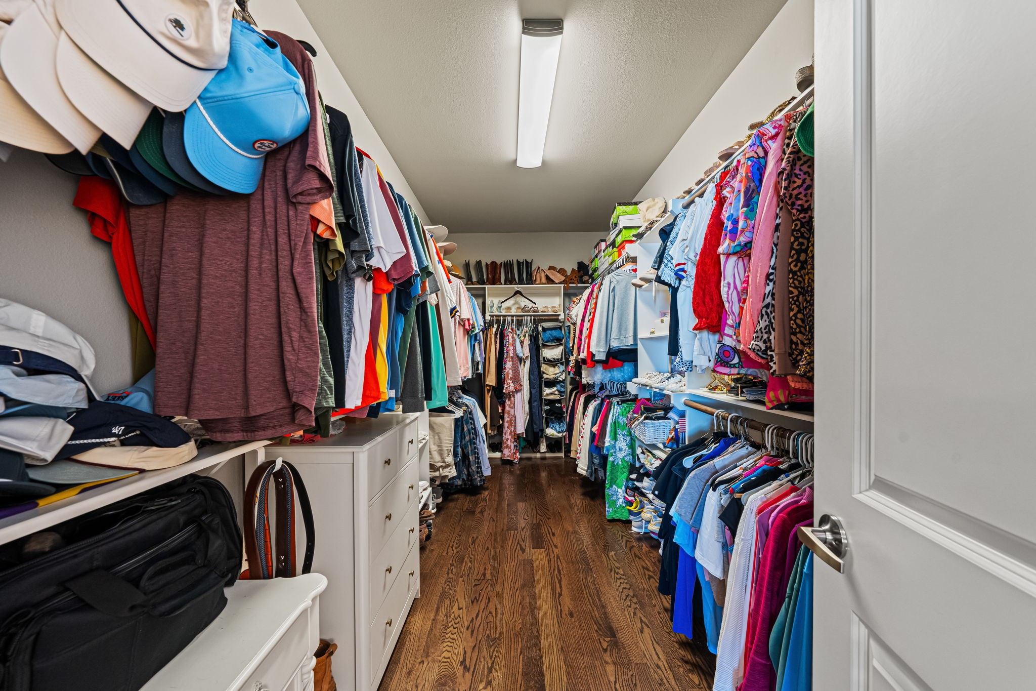 A spacious primary walk-in closet offers hanging space on both sides, with overhead shelving to keep seasonal pieces neatly tucked away.