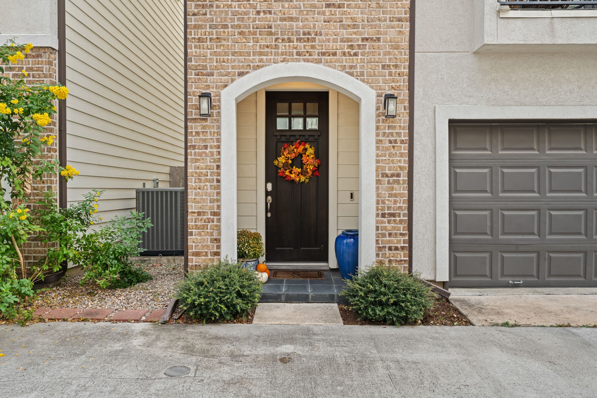 A graceful brick arch shelters the front entrance, setting an inviting tone before the door opens. Subtle contrasts in texture lend the approach an understated elegance.