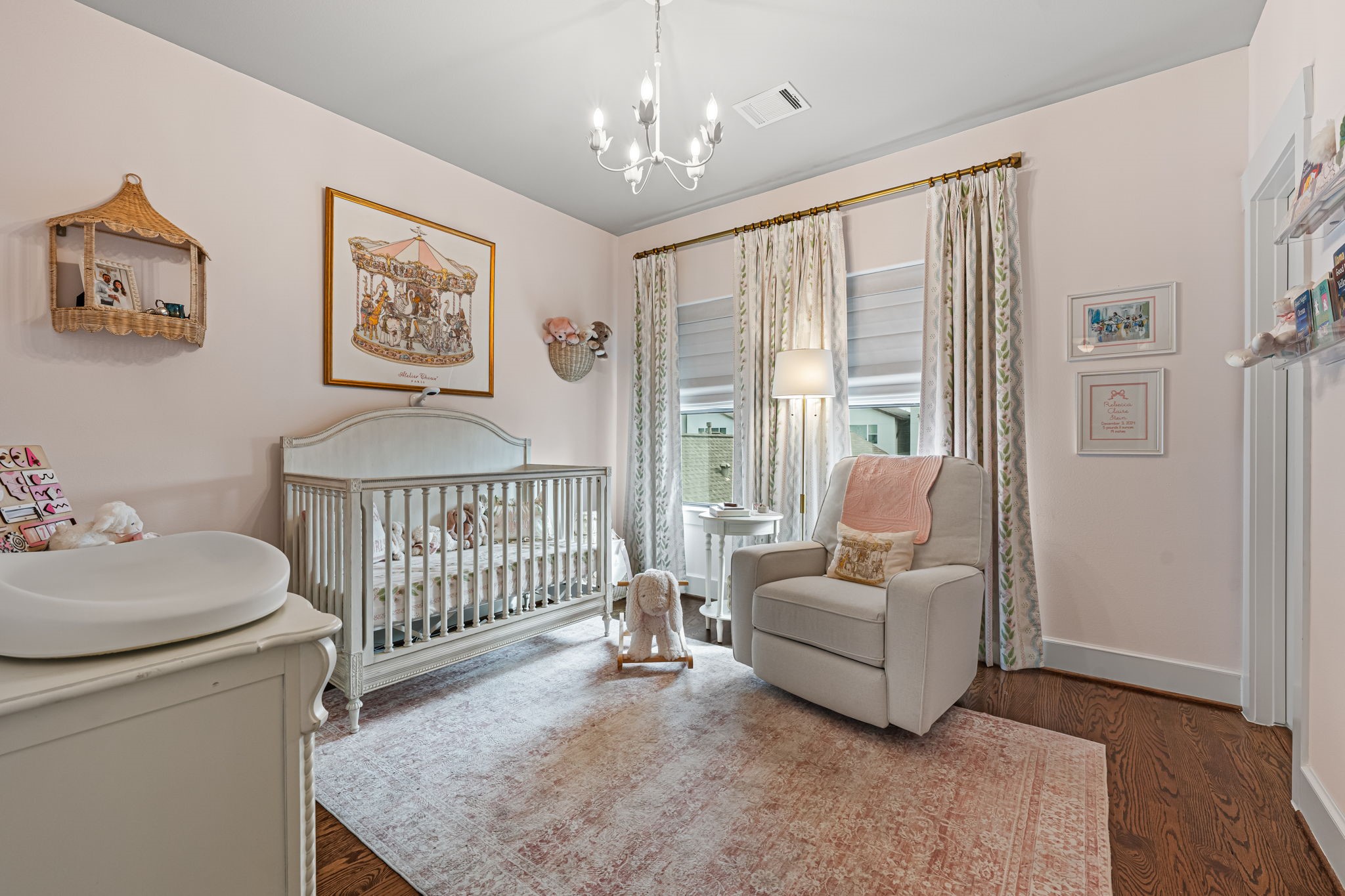 Wood flooring and delicate ceiling trim lend this secondary bedroom a quietly elegant character. Soft natural light keeps the versatile interior bright and restful. Note Visual Comfort chandelier is excluded.