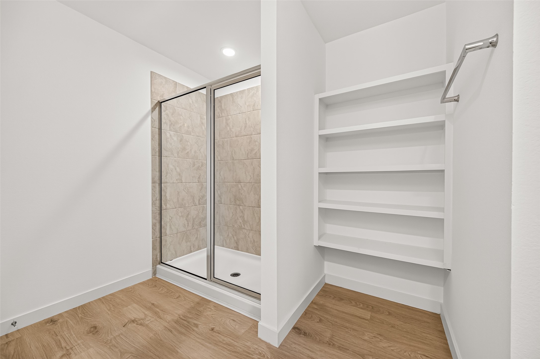 Walk-in shower, linen storage shelf, and towel rack.