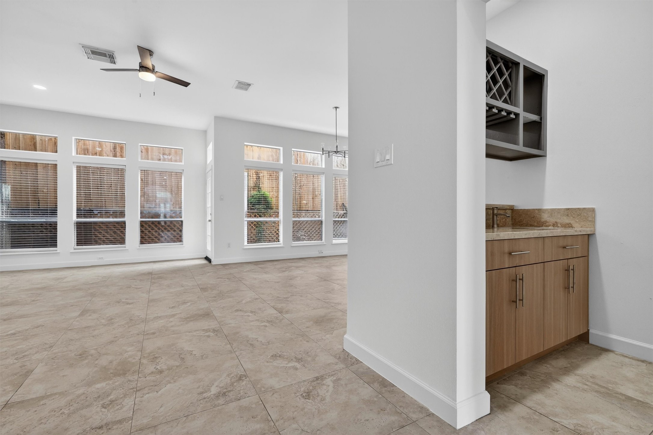Bright and airy open-concept living and dining area with soaring ceilings, oversized windows, and abundant natural light. Features include oversized tile flooring, modern wet bar with wine storage, recessed lighting, and neutral designer finishes. Spacious layout offers seamless indoor-outdoor flow and is ideal for entertaining.