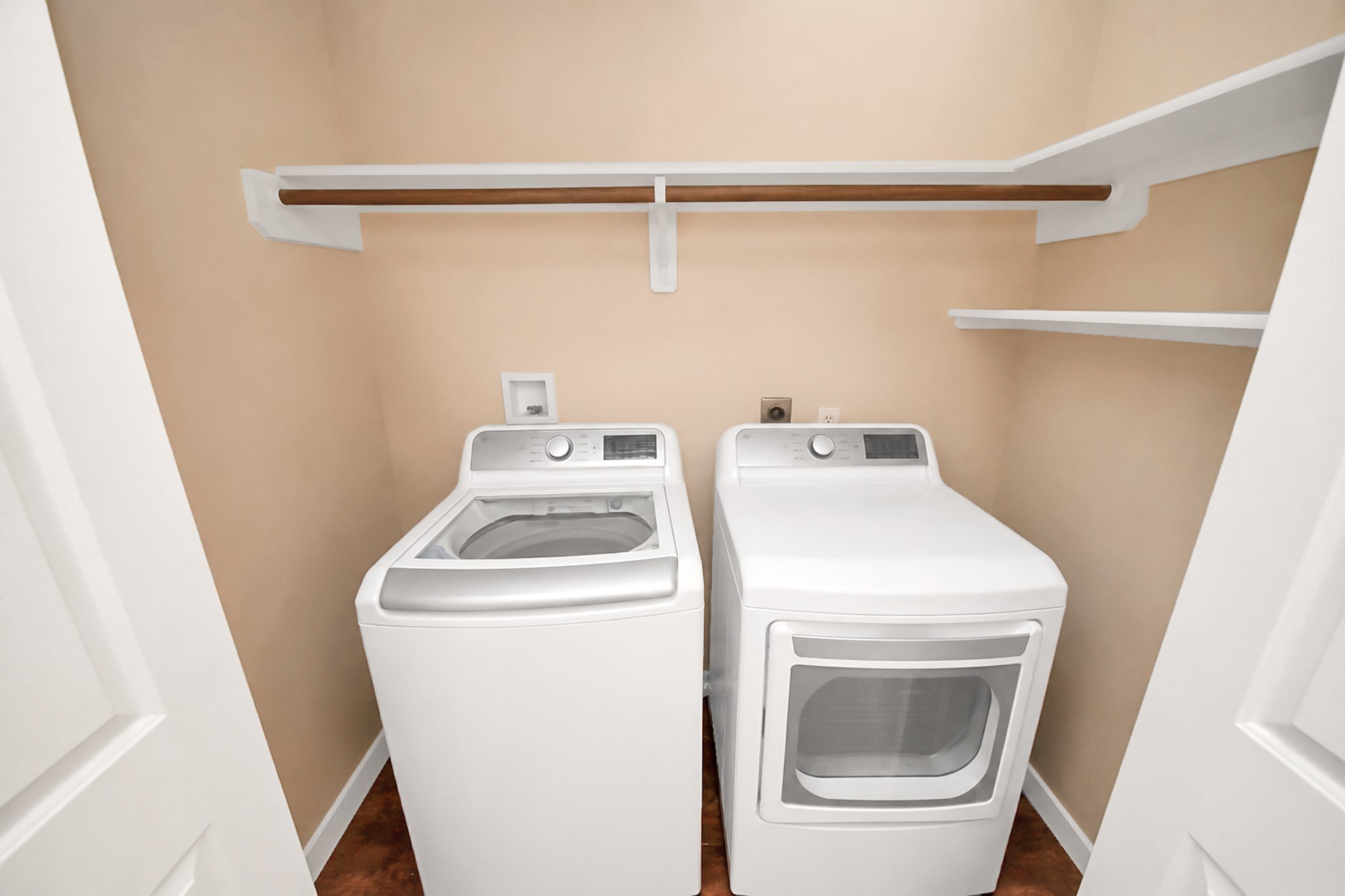 Indoor laundry area with full-size connections and overhead shelving.