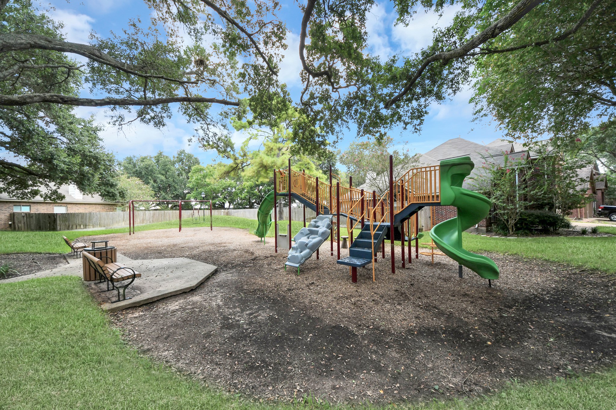 Nearby community playground shaded by mature trees.