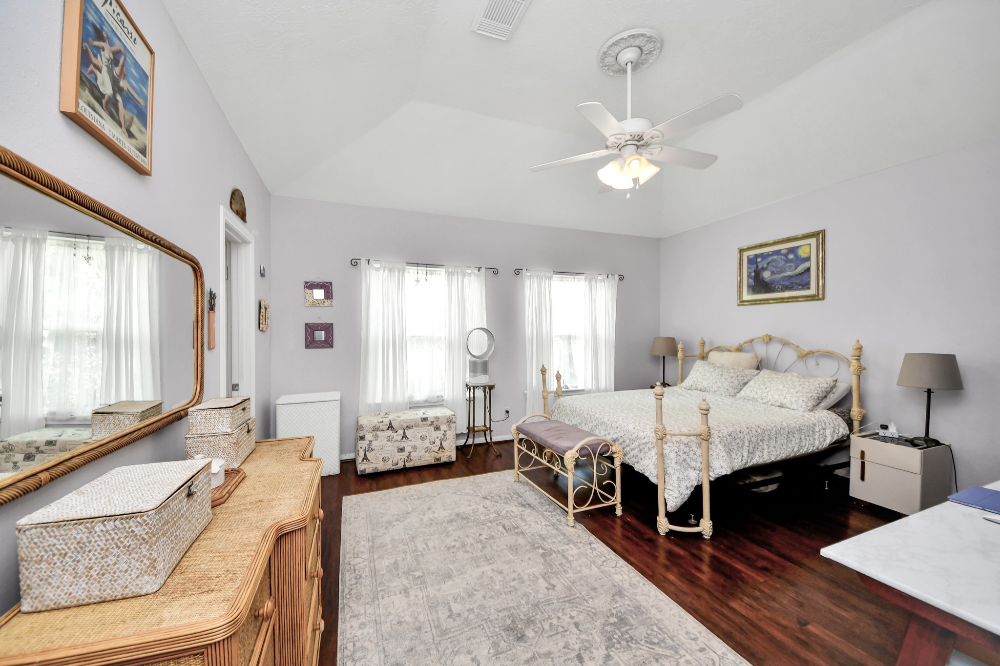 The oversized primary bedroom has a raised ceiling, multiple windows, and room for a sitting or work area.