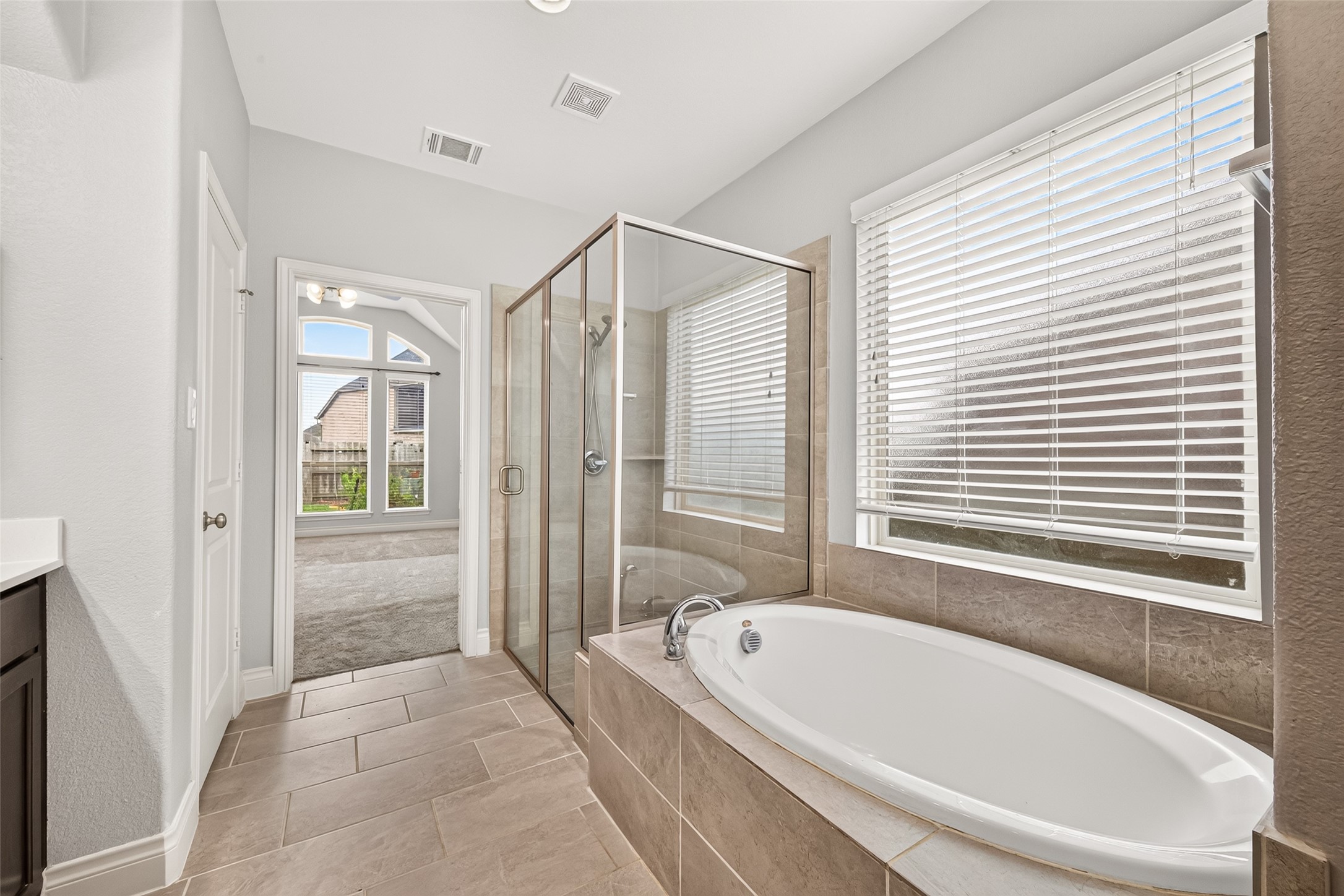 Elegant en-suite bath featuring a double vanity, relaxing soaking tub, and a glass-enclosed walk-in shower, creating a luxurious spa-like retreat.