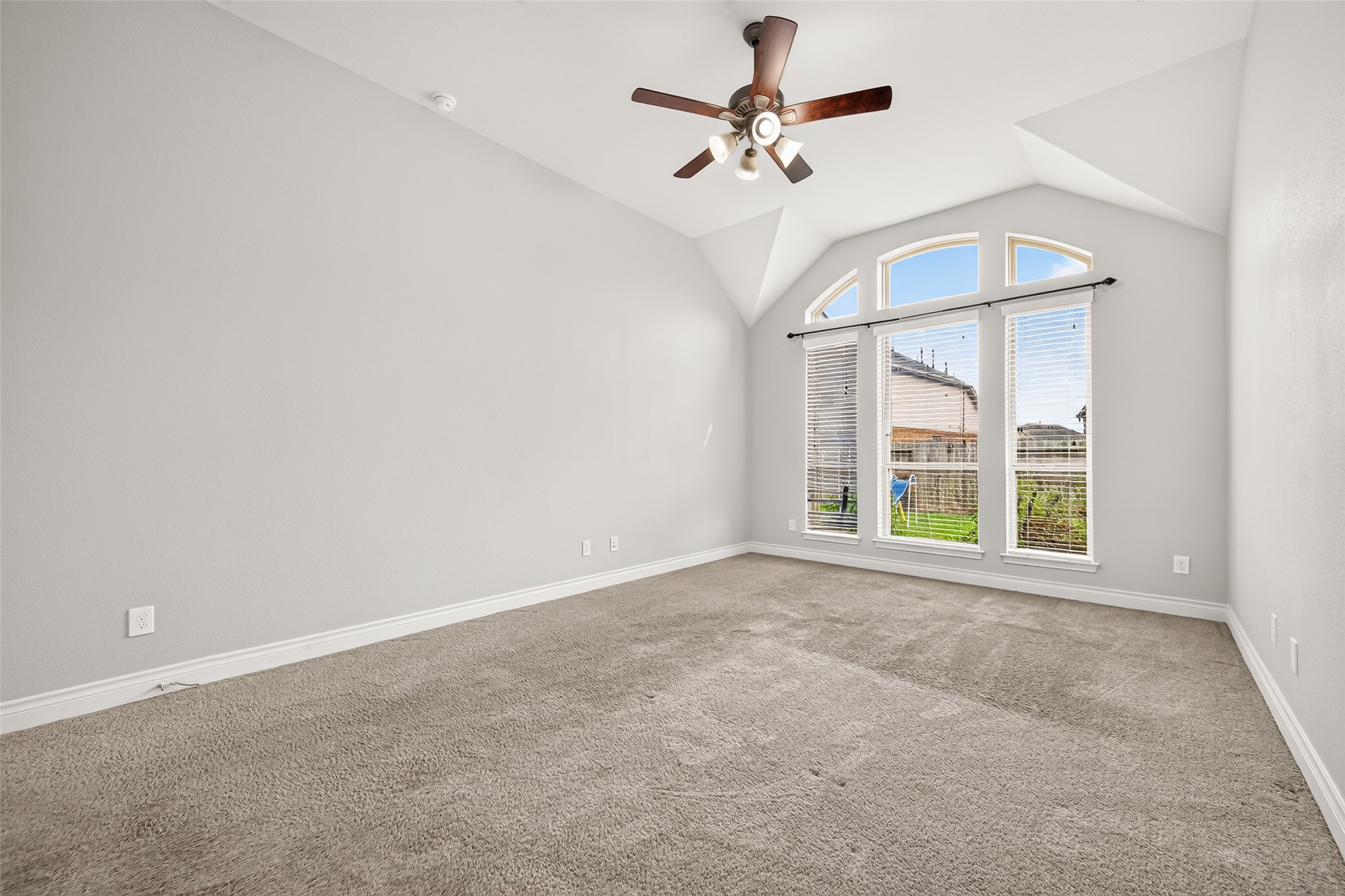 Spacious first-floor primary suite featuring soaring ceilings and large windows that fill the room with abundant natural light, creating a bright, airy, and inviting retreat