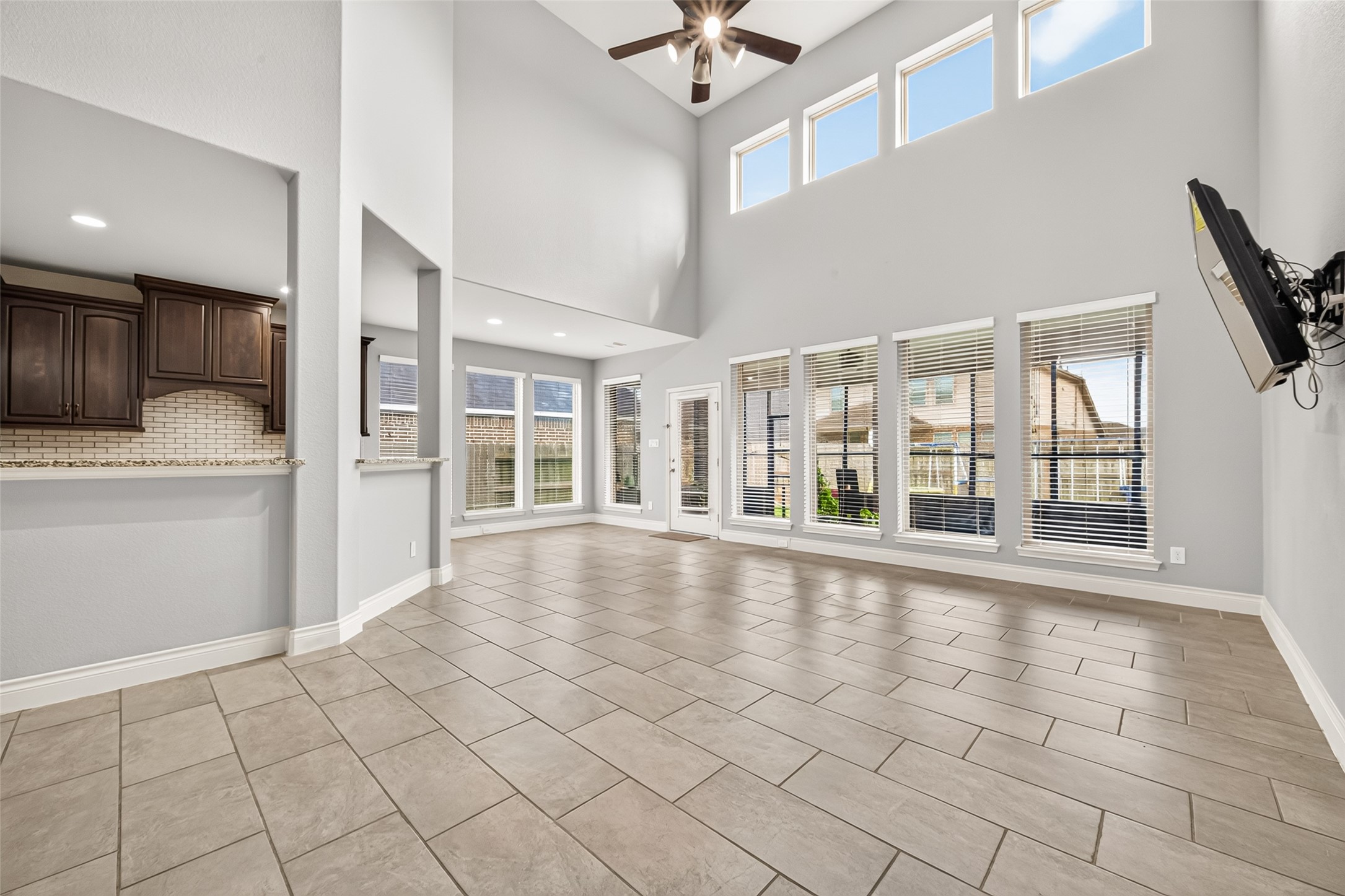 Stunning family room featuring soaring ceilings and a dramatic wall of windows that flood the space with abundant natural light, creating a bright, open, and inviting atmosphere