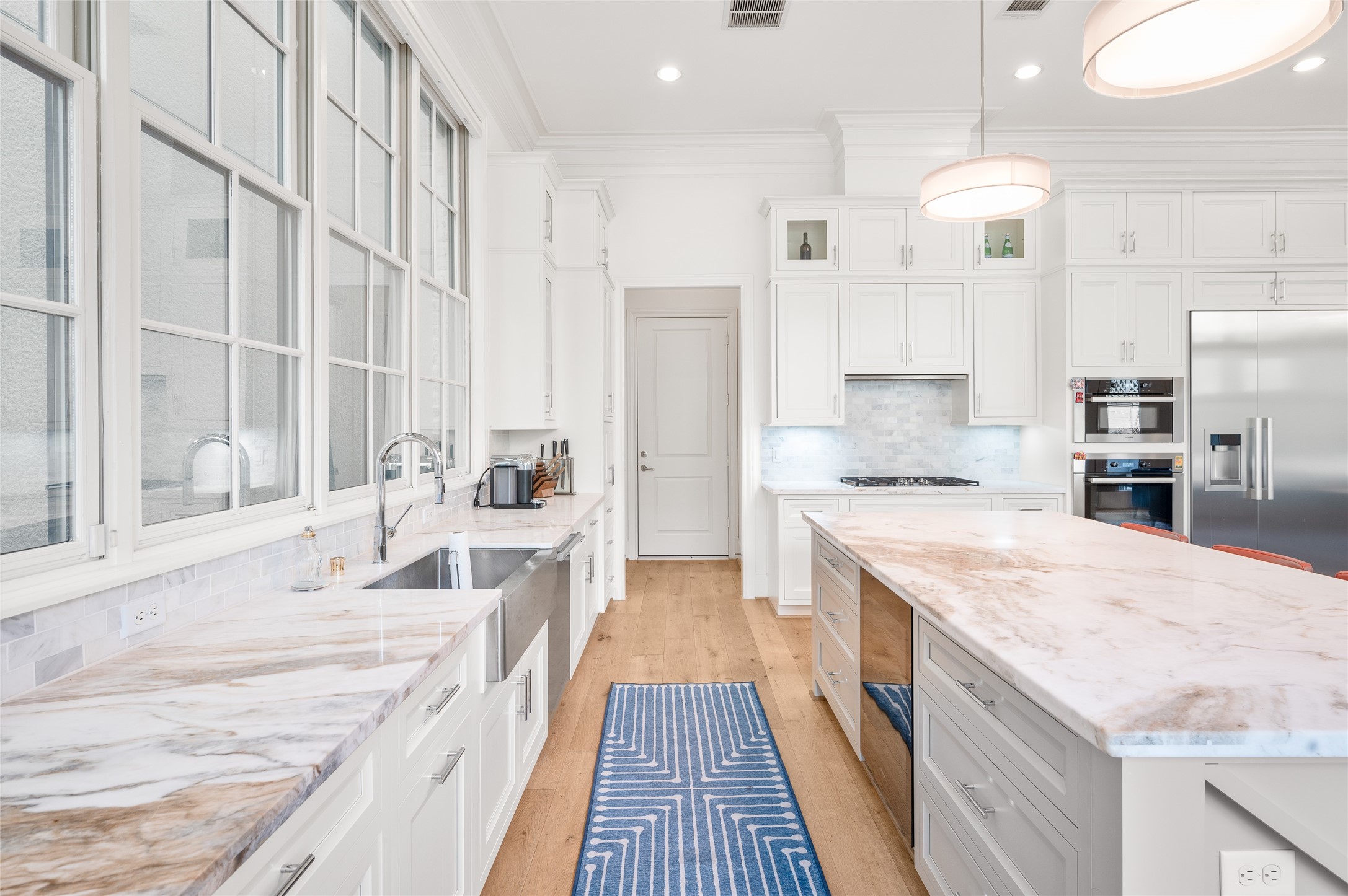 A closer look at the kitchen's marble countertops, farmhouse-style sink, polished fixtures, and tailored cabinetry with integrated storage.