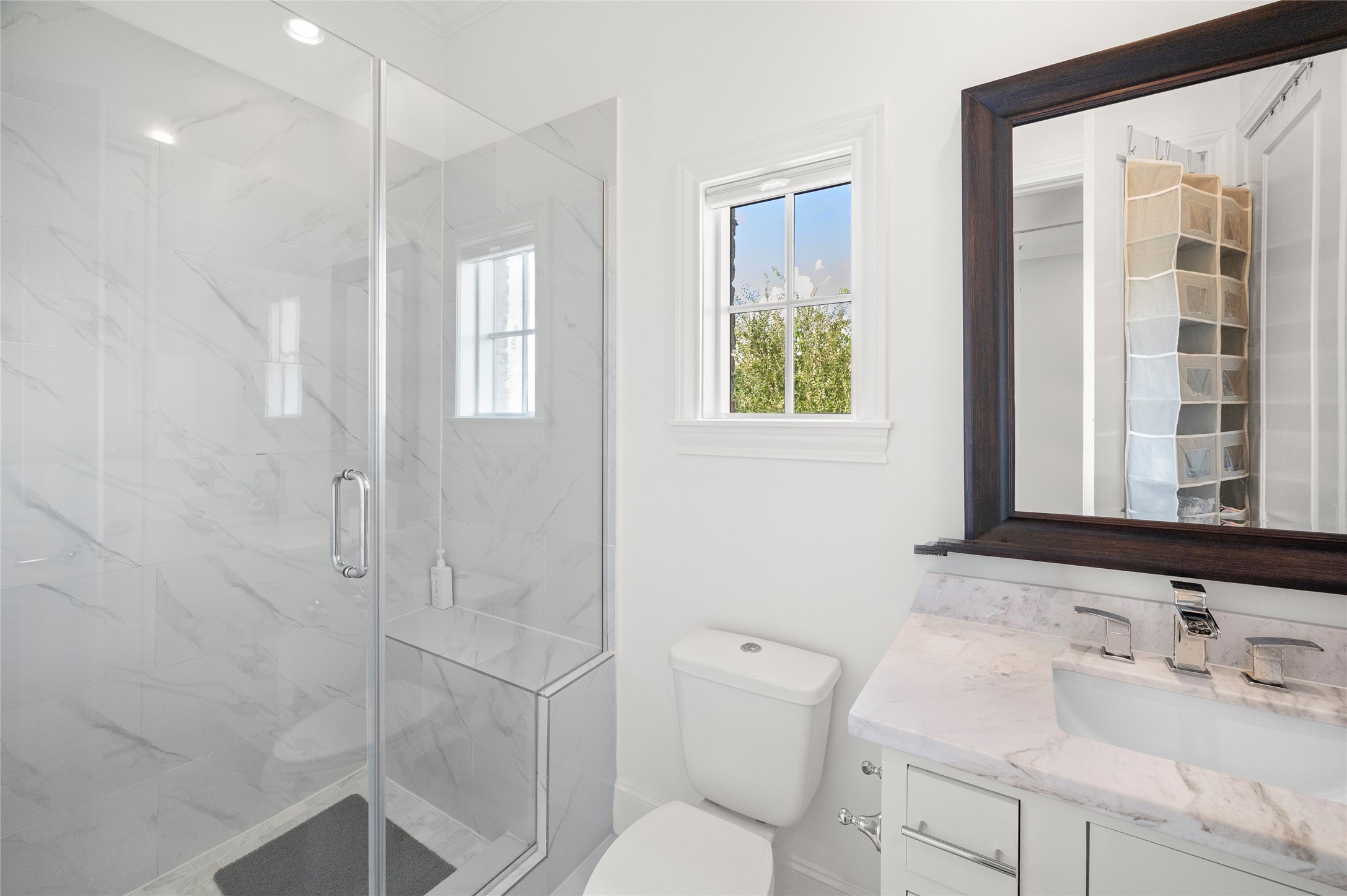 En-suite bath with standing glass shower and marble countertop.