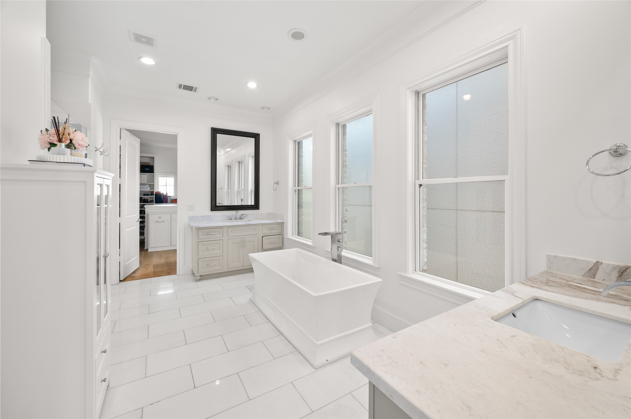 Beautifully appointed primary suite bath featuring a freestanding soaking tub, marble countertops, dual vanities, and abundant natural light.