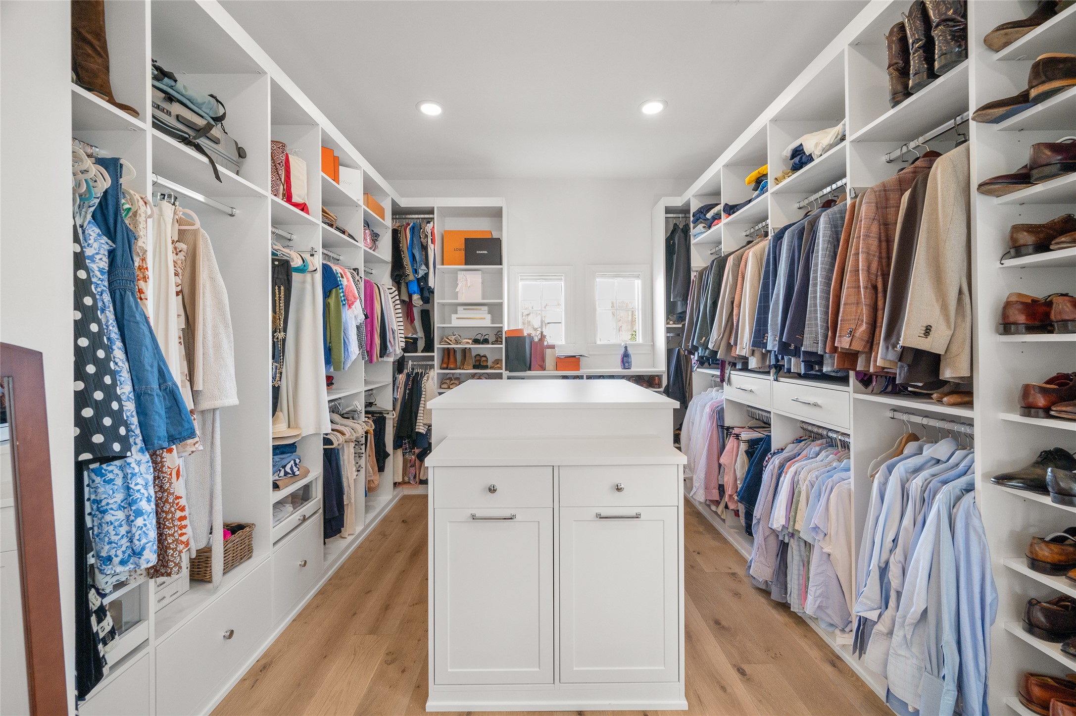 Generously sized walk-in closet with custom built-in shelving, hanging storage, drawers, and a central storage island.