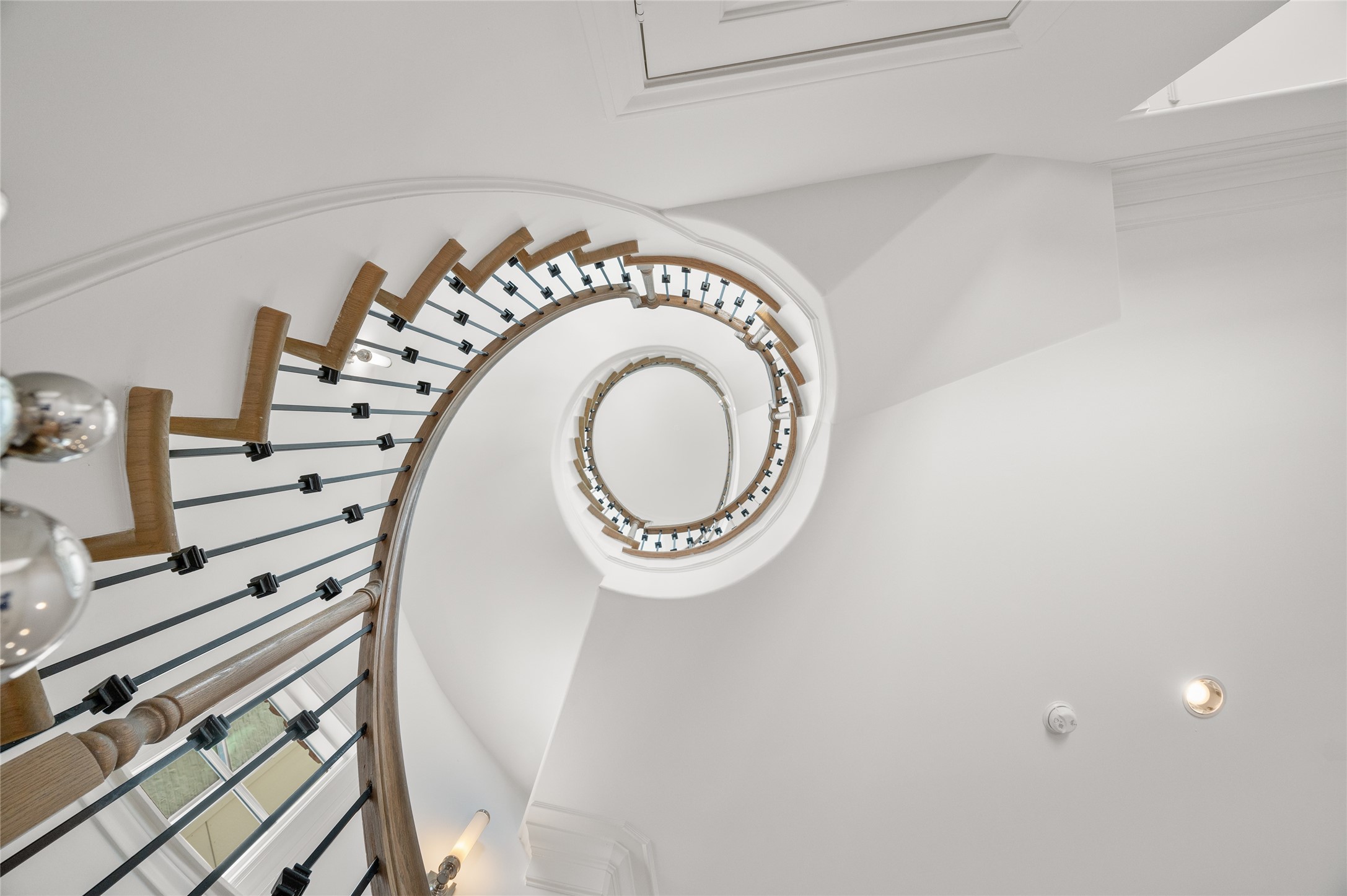 Striking curved staircase featuring natural wood treads, wrought-iron balusters, and a sculptural design spanning multiple levels.