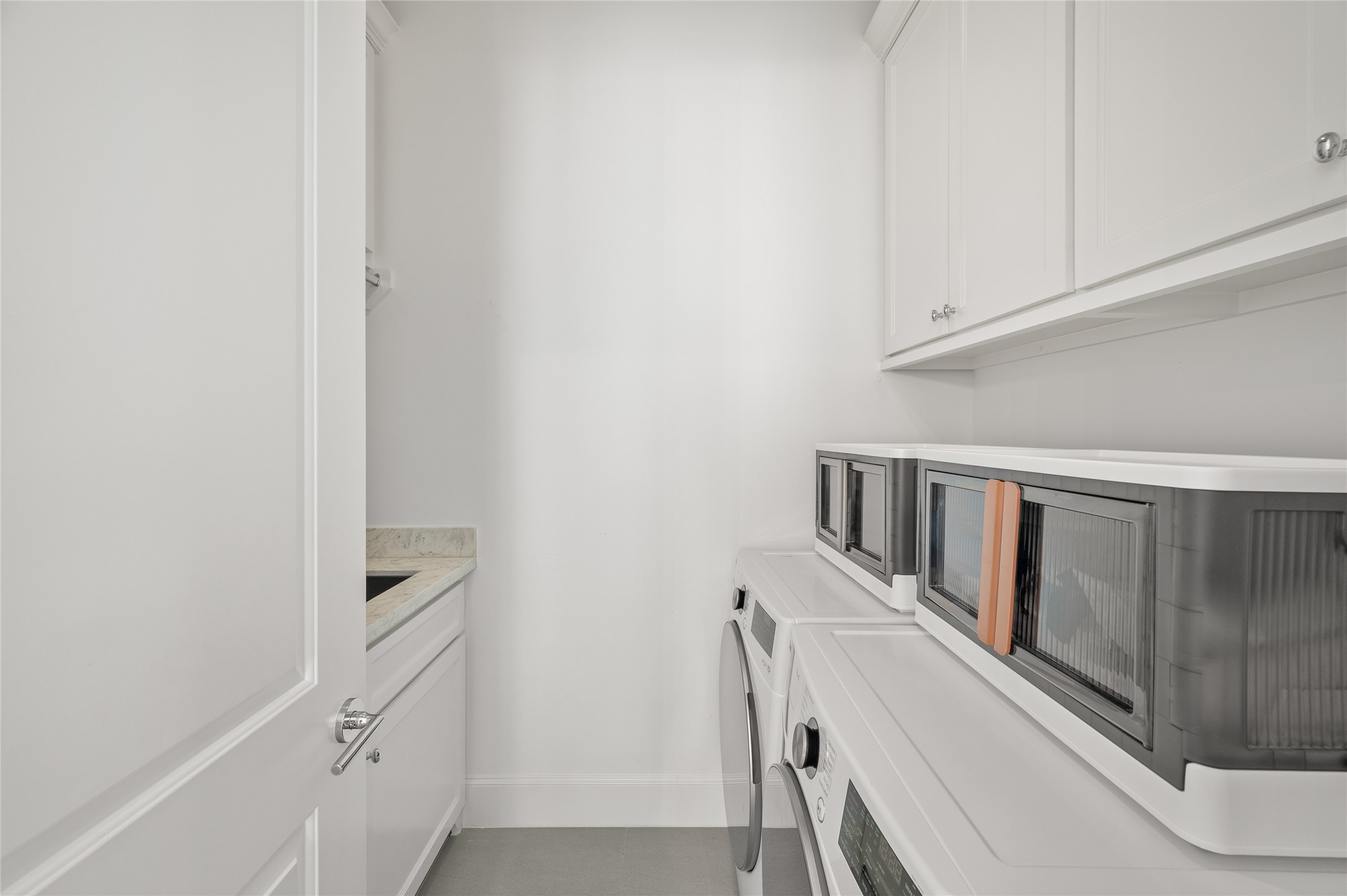 Dedicated utility room featuring side-by-side washer and dryer, upper cabinetry, countertop space, and a utility sink.