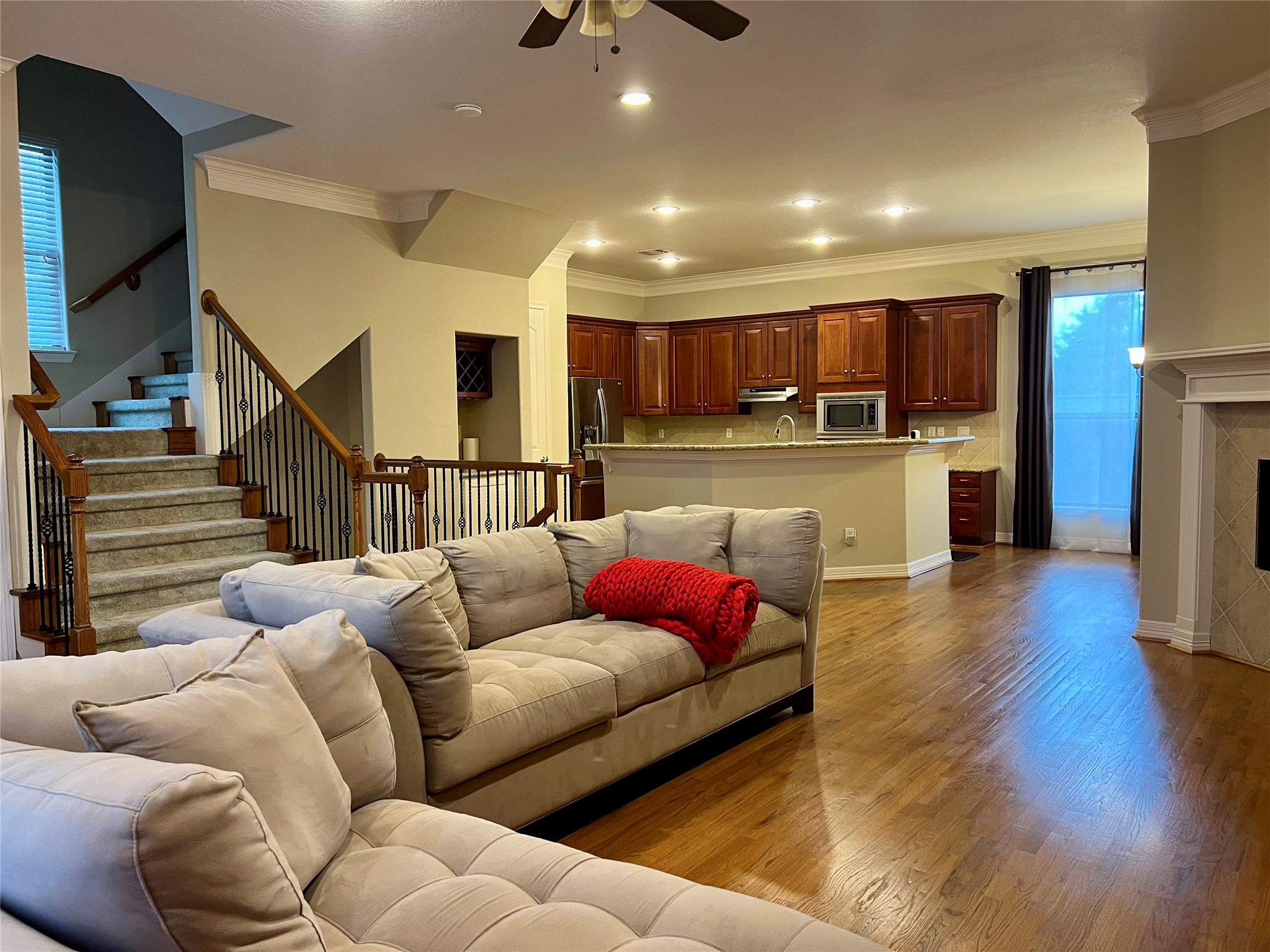 This inviting open-concept living space features hardwood floors, a cozy fireplace, and a modern kitchen with rich wood cabinetry and stainless steel appliances. The living area includes comfortable seating and access to a staircase, creating a warm and functional environment for family gatherings. This inviting open-concept living space features hardwood floors, a cozy fireplace, and a modern kitchen with rich wood cabinetry and stainless steel appliances. The living area includes comfortable seating and access to a staircase, creating a warm and functional environment for family gatherings.