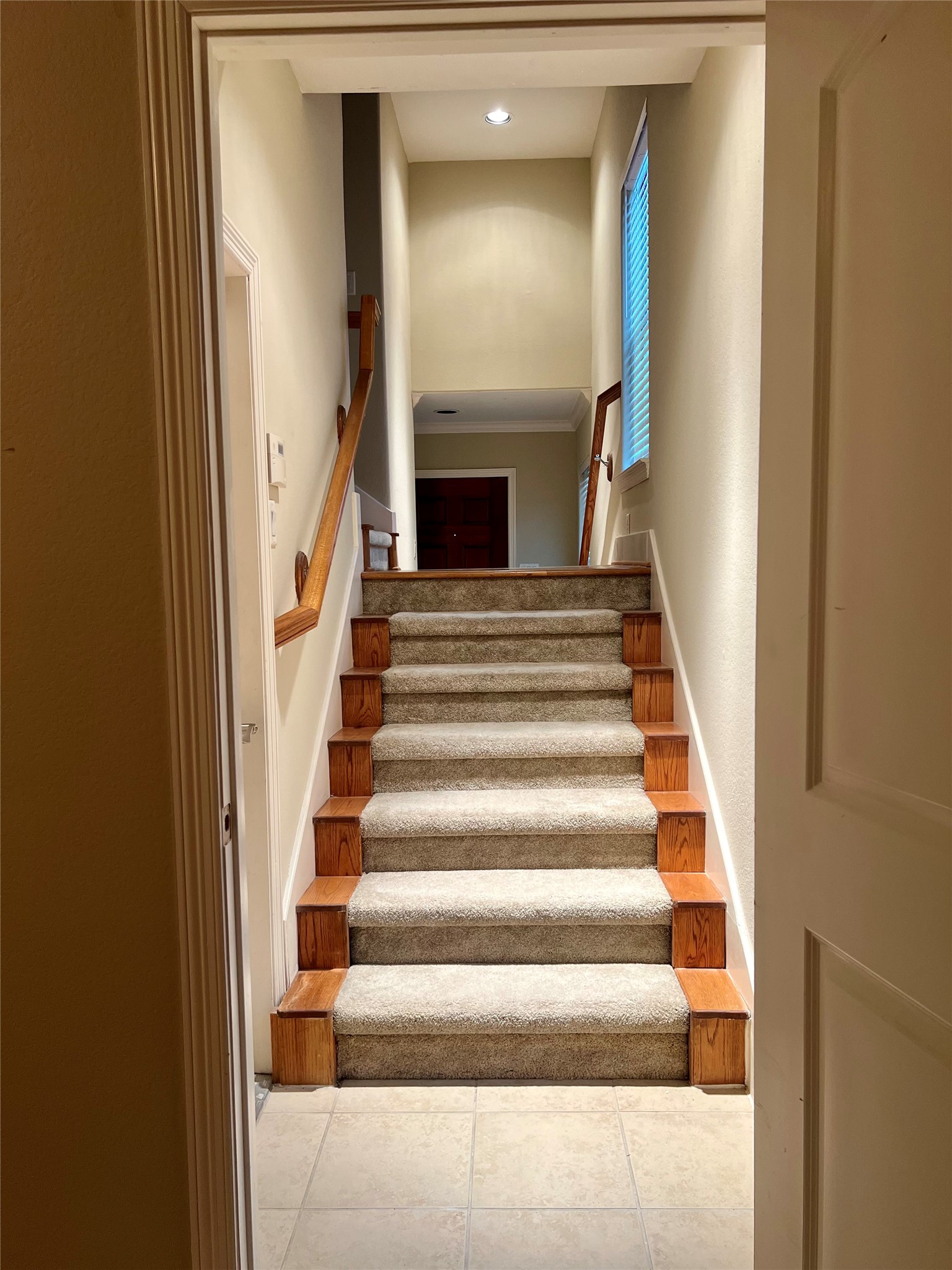 This photo shows a well-lit, carpeted staircase with wooden accents, leading up to the second-floor living area. The neutral walls and windows provide a bright, welcoming atmosphere. This photo shows a well-lit, carpeted staircase with wooden accents, leading up to the second-floor living area. The neutral walls and windows provide a bright, welcoming atmosphere.