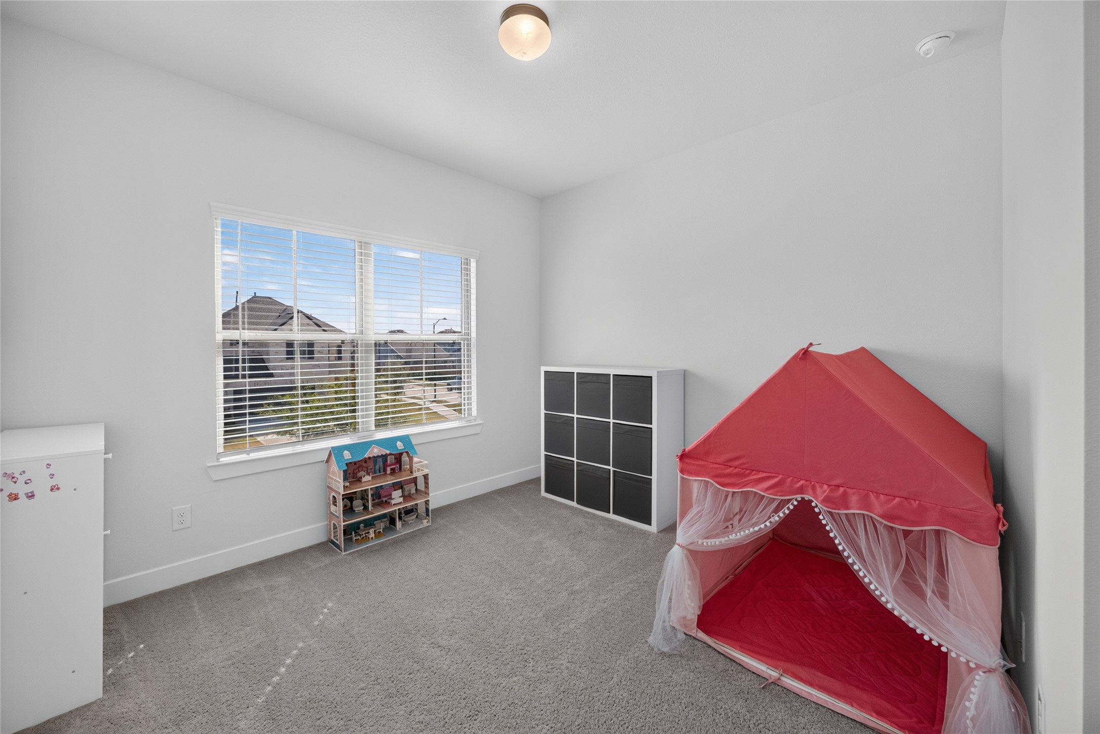 Currently arranged as a playroom, this upstairs bedroom demonstrates the flexibility of the homes additional living spaces. A large window brings in natural light, while the open floor area accommodates furniture, toys or a study setup. Neutral finishes make it easy to adapt the room to changing needs.