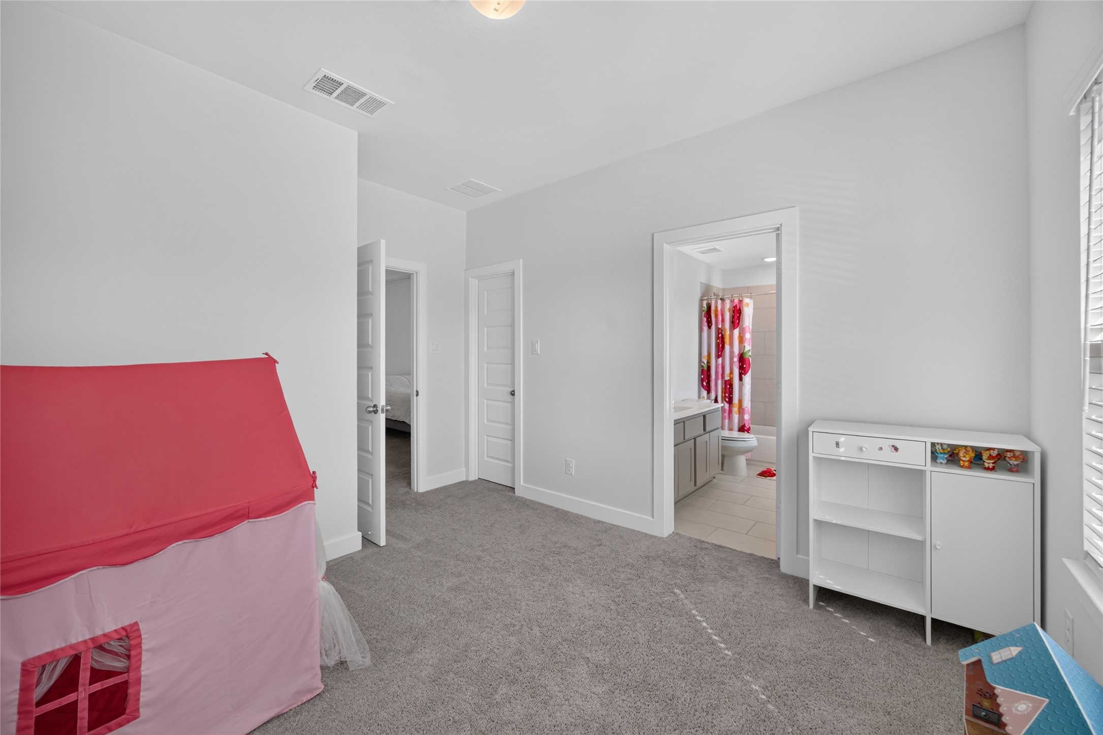 This alternate angle shows the secondary bedrooms closet and direct access to an adjoining bathroom. The layout leaves room for bedroom furnishings or a combination of sleeping and study areas. Carpeting and neutral walls continue the consistent finishes found throughout the upstairs bedrooms.