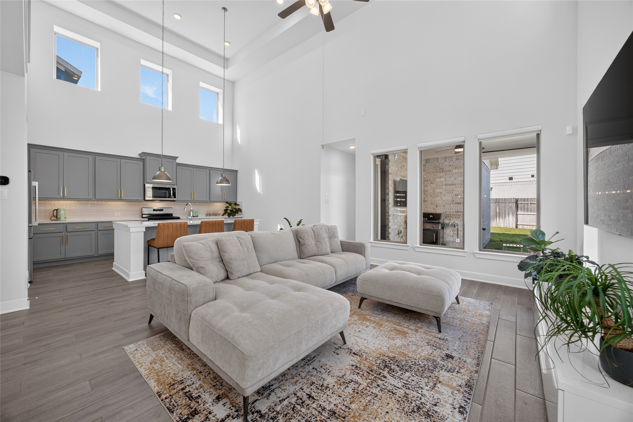 The family room features a soaring two-story ceiling and upper windows that draw natural light deep into the home. The kitchen remains connected to the seating area, allowing conversation to flow while meals are prepared. Windows along the rear wall provide views toward the covered patio and backyard. The family room features a soaring two-story ceiling and upper windows that draw natural light deep into the home. The kitchen remains connected to the seating area, allowing conversation to flow while meals are prepared. Windows along the rear wall provide views toward the covered patio and backyard.