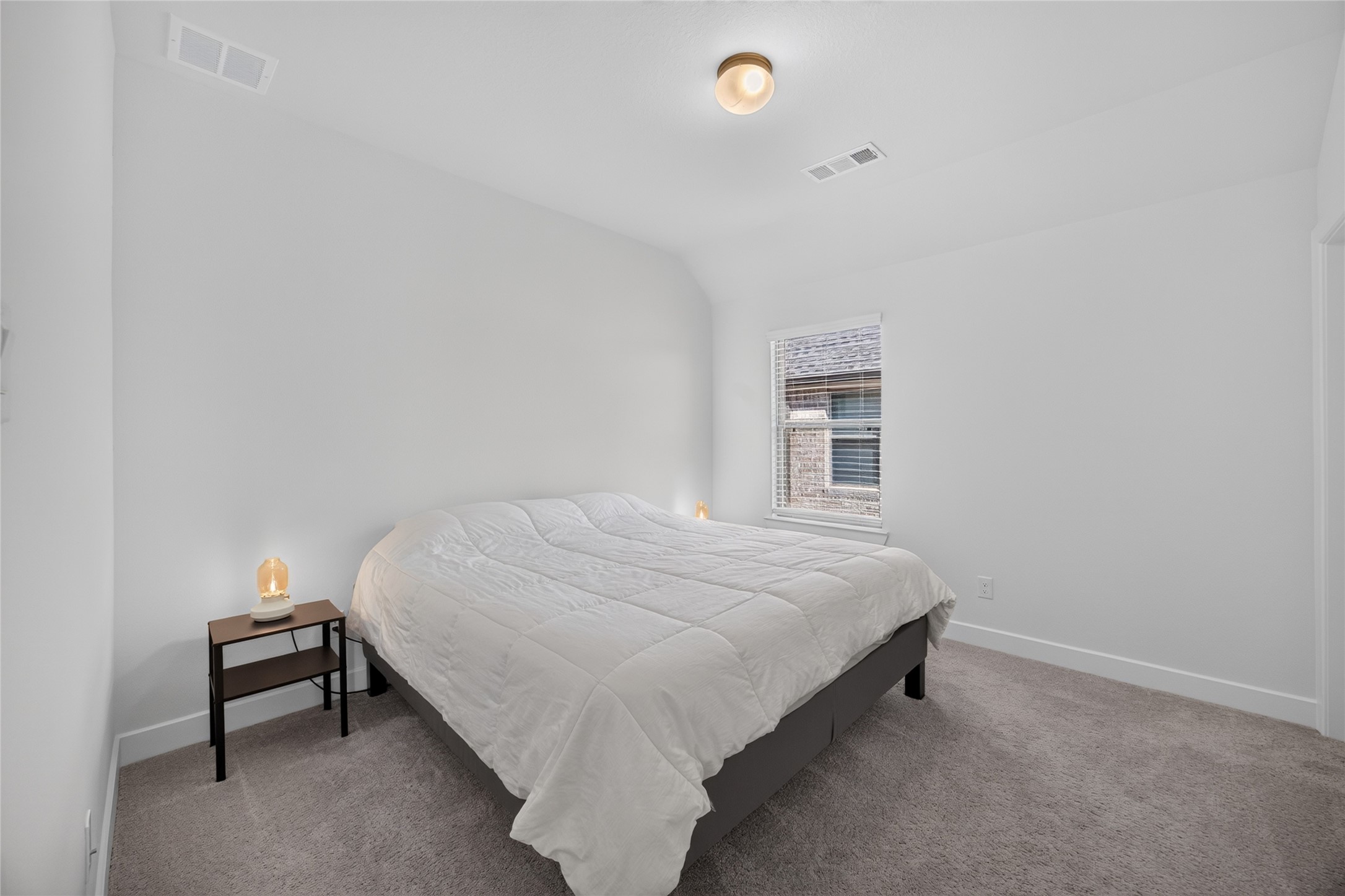 This upstairs secondary bedroom features neutral walls, carpeting and a window with blinds. The simple layout accommodates a bed, bedside furniture and additional storage pieces. Located away from the main gathering areas, the room provides a comfortable setting for sleeping, studying or hosting guests.