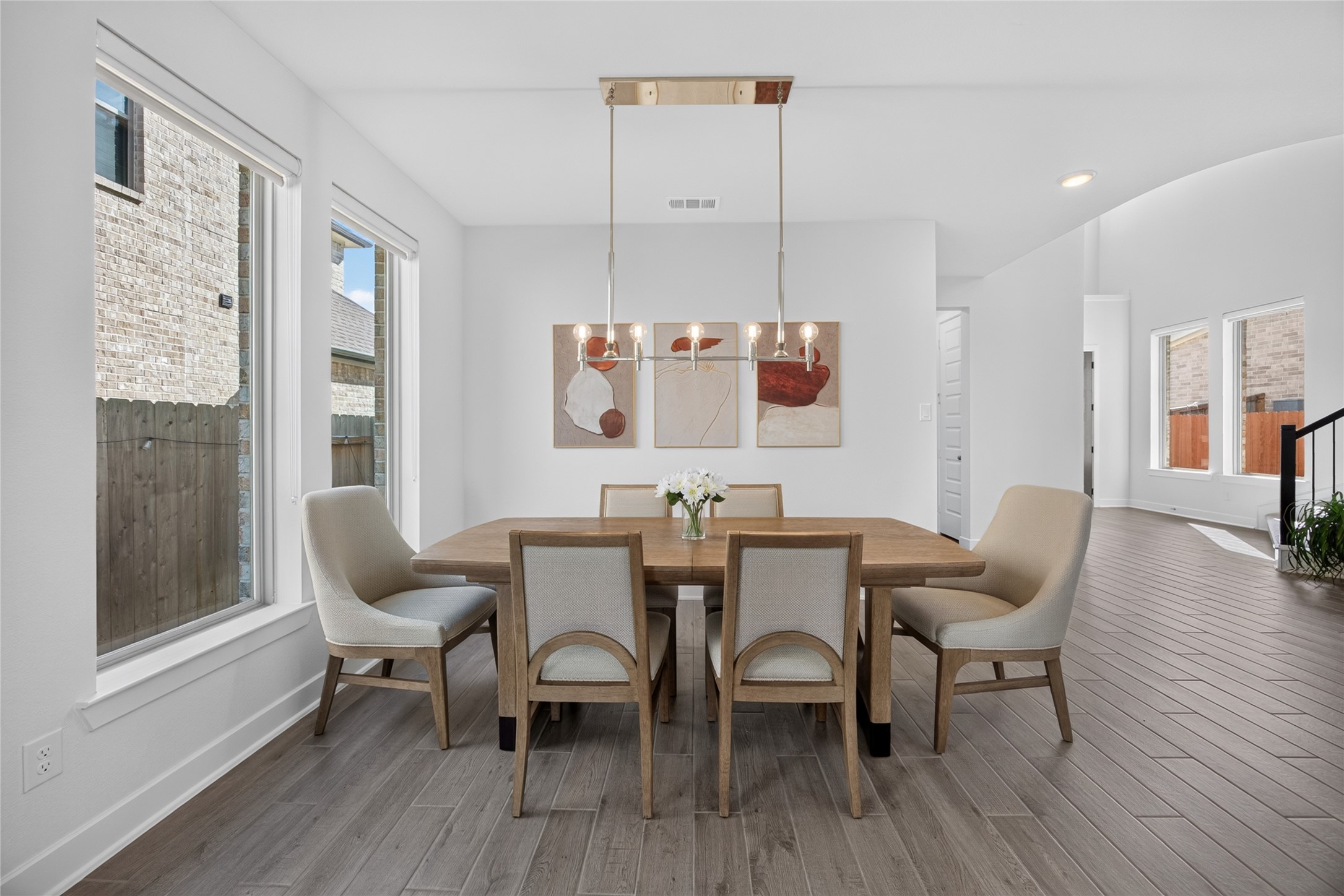 The dining area combines generous natural light with a contemporary linear chandelier for a welcoming gathering space. Tall windows frame the table, and the open layout accommodates both casual meals and more formal occasions. Its proximity to the kitchen makes serving and entertaining convenient. The dining area combines generous natural light with a contemporary linear chandelier for a welcoming gathering space. Tall windows frame the table, and the open layout accommodates both casual meals and more formal occasions. Its proximity to the kitchen makes serving and entertaining convenient.