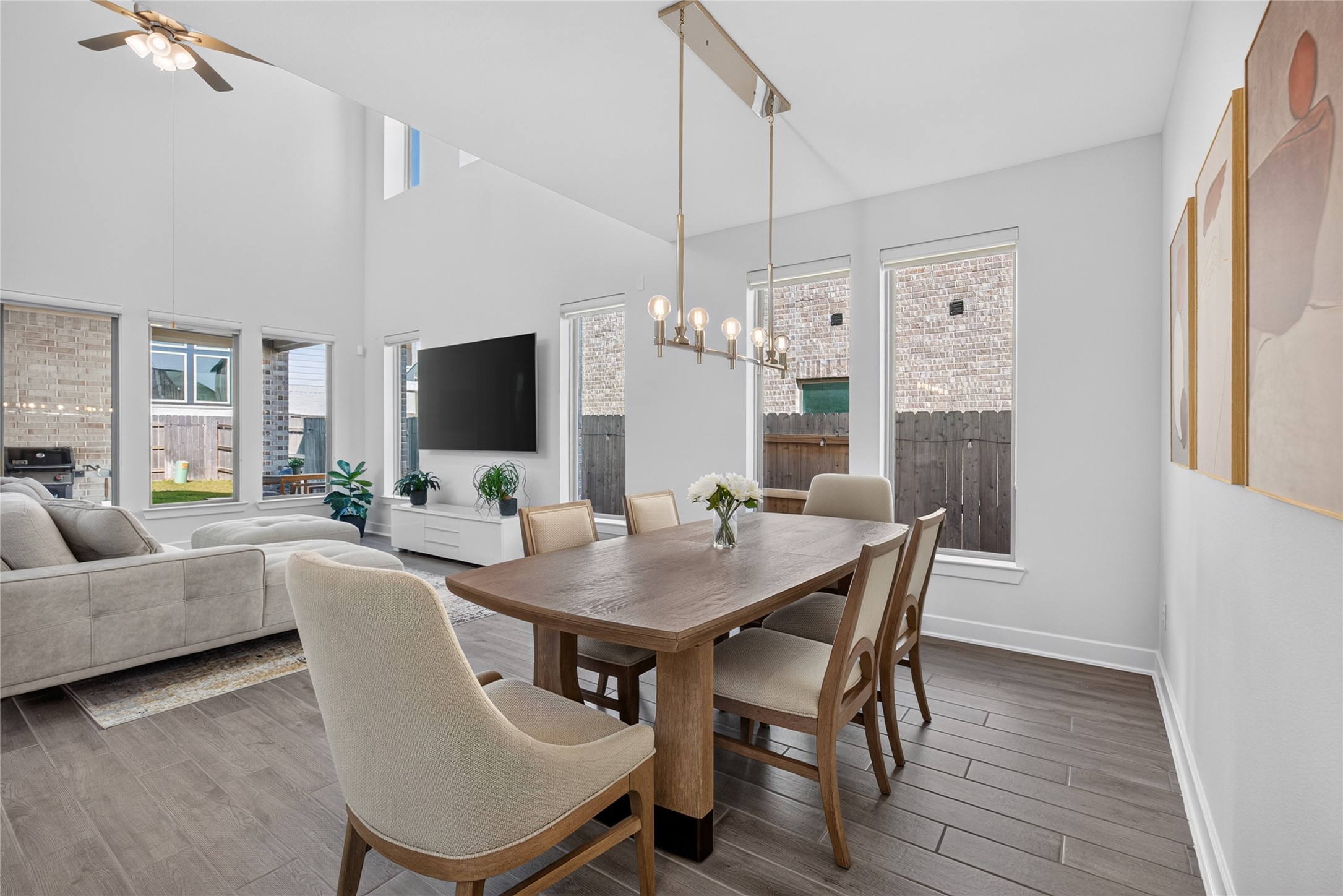 Viewed from the dining area, the homes connected layout brings the main gathering spaces together. The dining table sits beneath a statement chandelier, with uninterrupted views into the family room. Tall windows, neutral walls and continuous flooring give the space a bright, cohesive feel. Viewed from the dining area, the homes connected layout brings the main gathering spaces together. The dining table sits beneath a statement chandelier, with uninterrupted views into the family room. Tall windows, neutral walls and continuous flooring give the space a bright, cohesive feel.