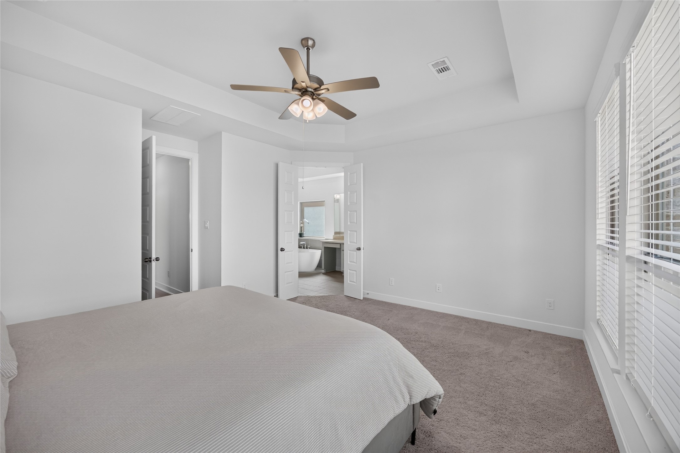 This reverse view of the primary suite highlights its spacious layout, architectural ceiling detail and direct access to the adjoining bathroom. The bedrooms placement on the first floor separates it from the three upstairs bedrooms, creating a comfortable space to retreat at the end of the day.