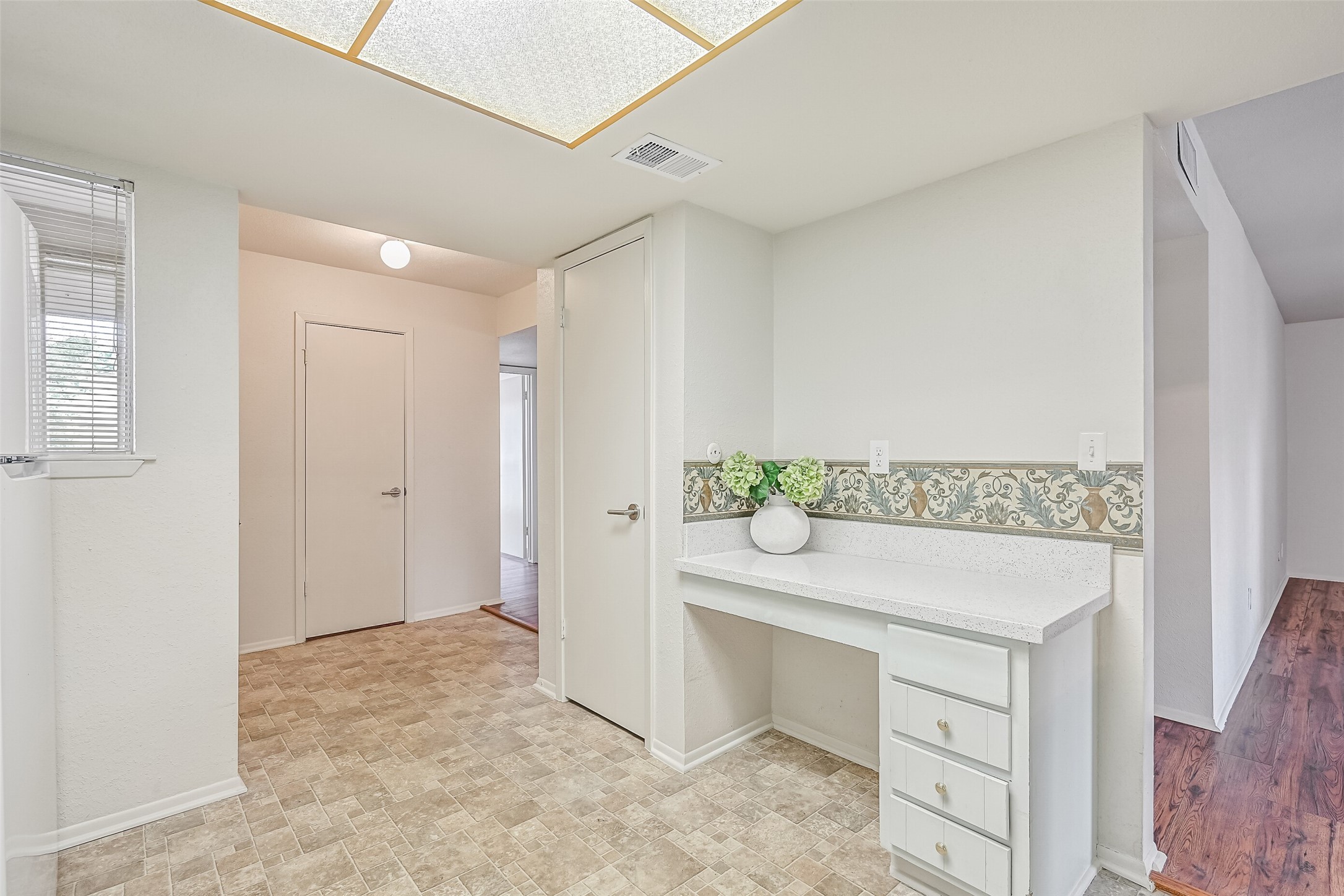 Tucked just off the kitchen, this handy built-in desk area offers a dedicated spot for a laptop, household paperwork or meal planning. Speckled countertops, a decorative backsplash & drawers provide useful workspace and storage, while a nearby window brings natural light into the kitchen.