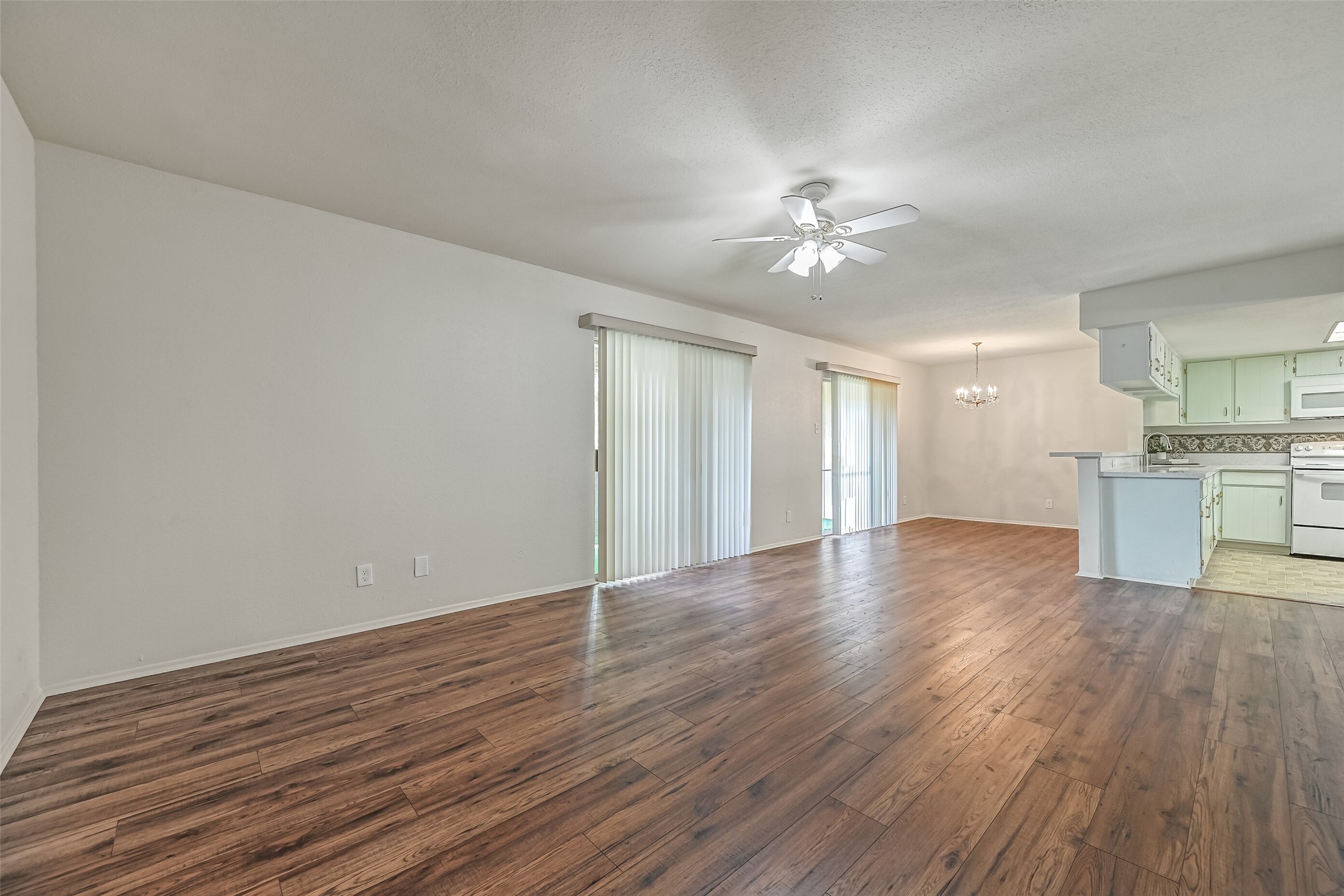 Looking across the main living areas, you'll appreciate the open floor plan, wood-look flooring & natural light filtering through the sliding glass doors. The living room flows into a separate dining space, with a breakfast bar connecting the kitchen to the rest of the home.