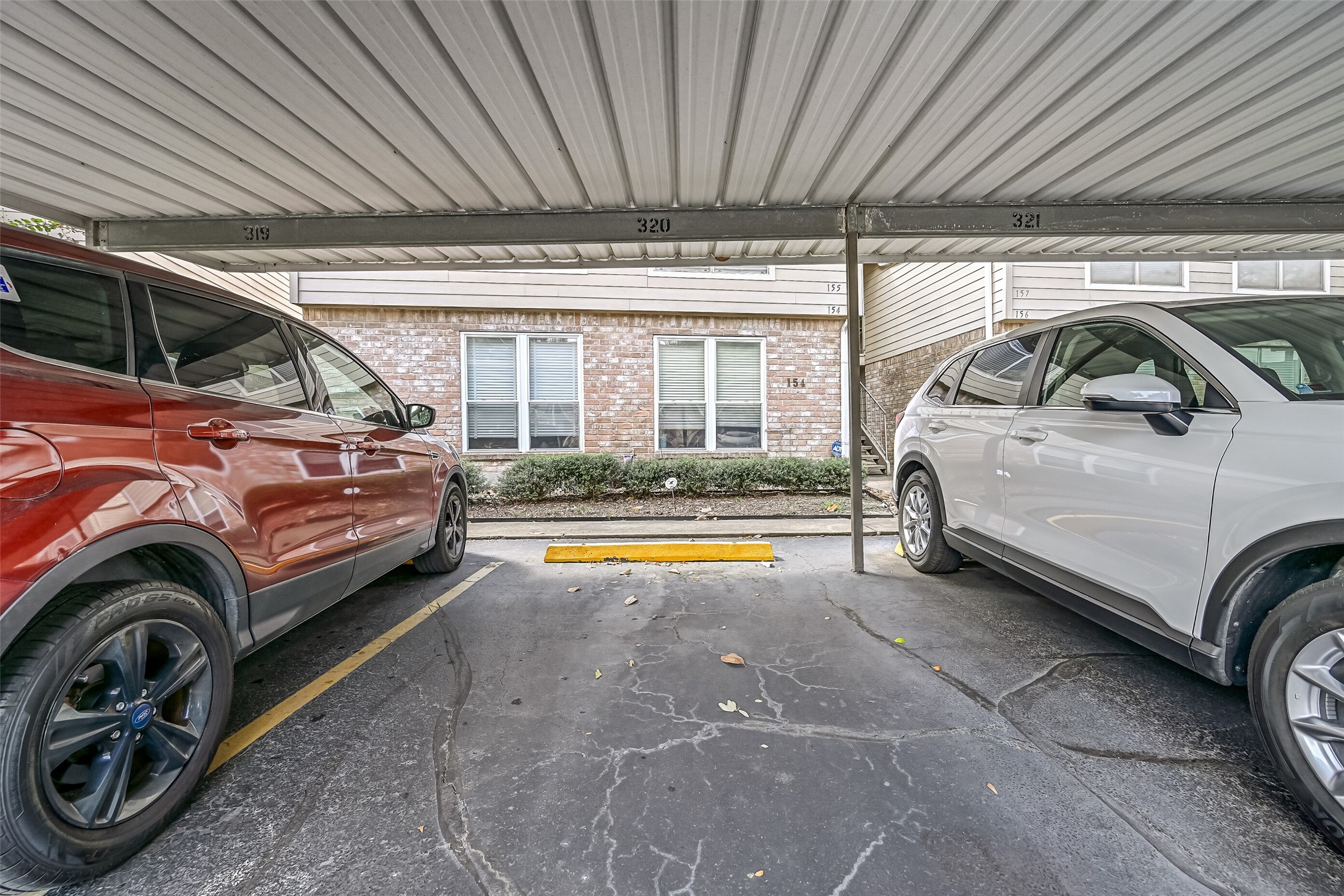 Covered parking provides protection from the elements, with parking space #320 pictured here. The covered parking area is located near the residential buildings, with sidewalks & stairway access to the second-floor units. An added benefit for residents of this Northwest Houston condominium community.