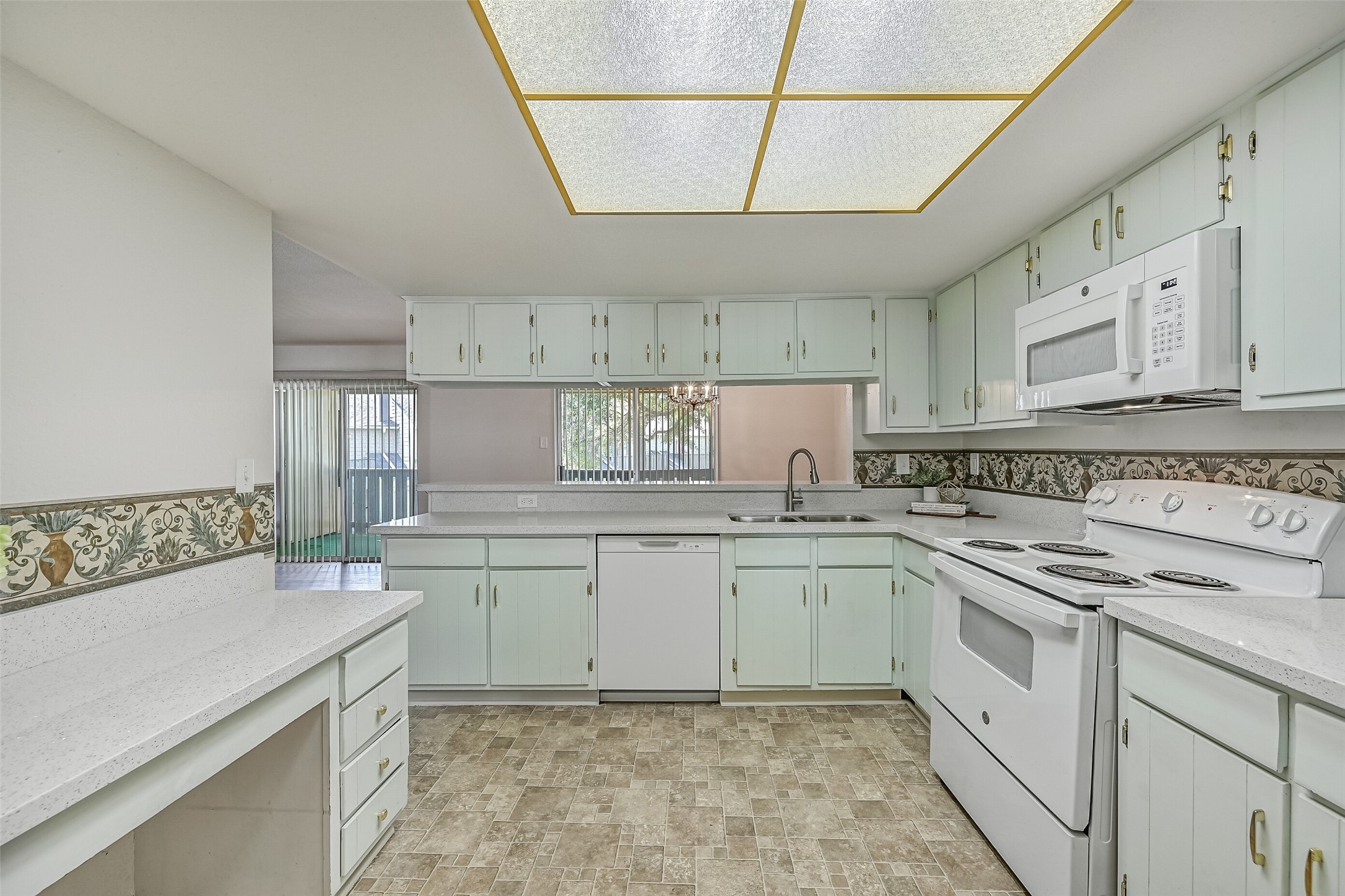 From inside the kitchen, enjoy an open view into the adjoining dining & living areas through the wide breakfast bar. Generous cabinet storage, a double-basin stainless steel sink, dishwasher & electric range make this kitchen practical, while the open design keeps the main living spaces connected.