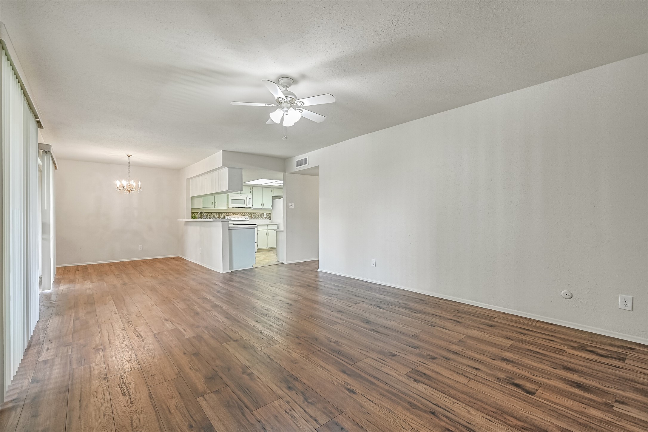 The generously sized living room offers plenty of flexibility for arranging your furniture, with attractive wood-look flooring, neutral walls & a lighted ceiling fan. An open layout connects the living room to the dining area & kitchen, creating an easy flow throughout the main living spaces.