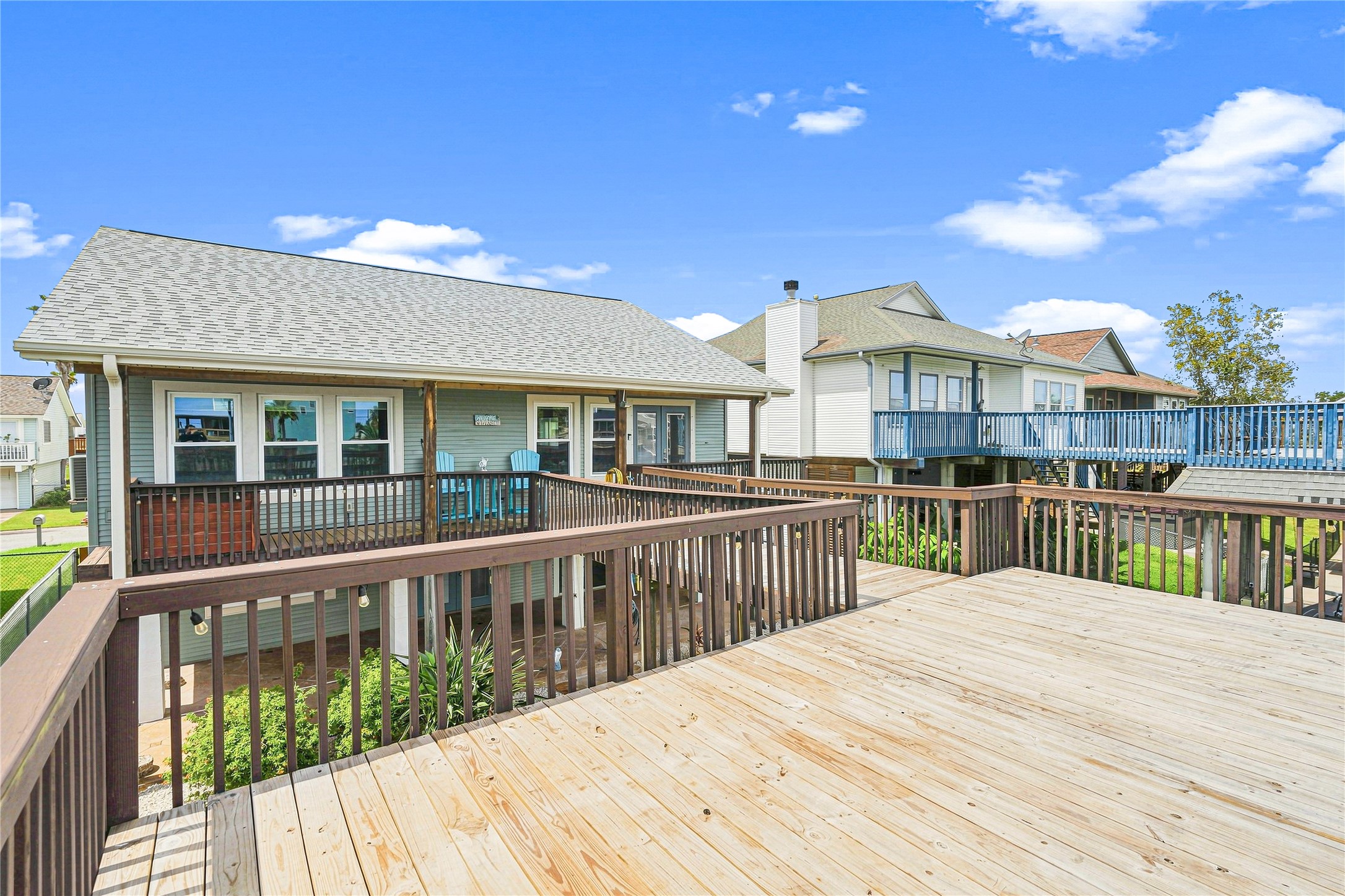 Spacious elevated deck perfect for outdoor entertaining, with charming views of neighboring homes and a bright, inviting exterior.