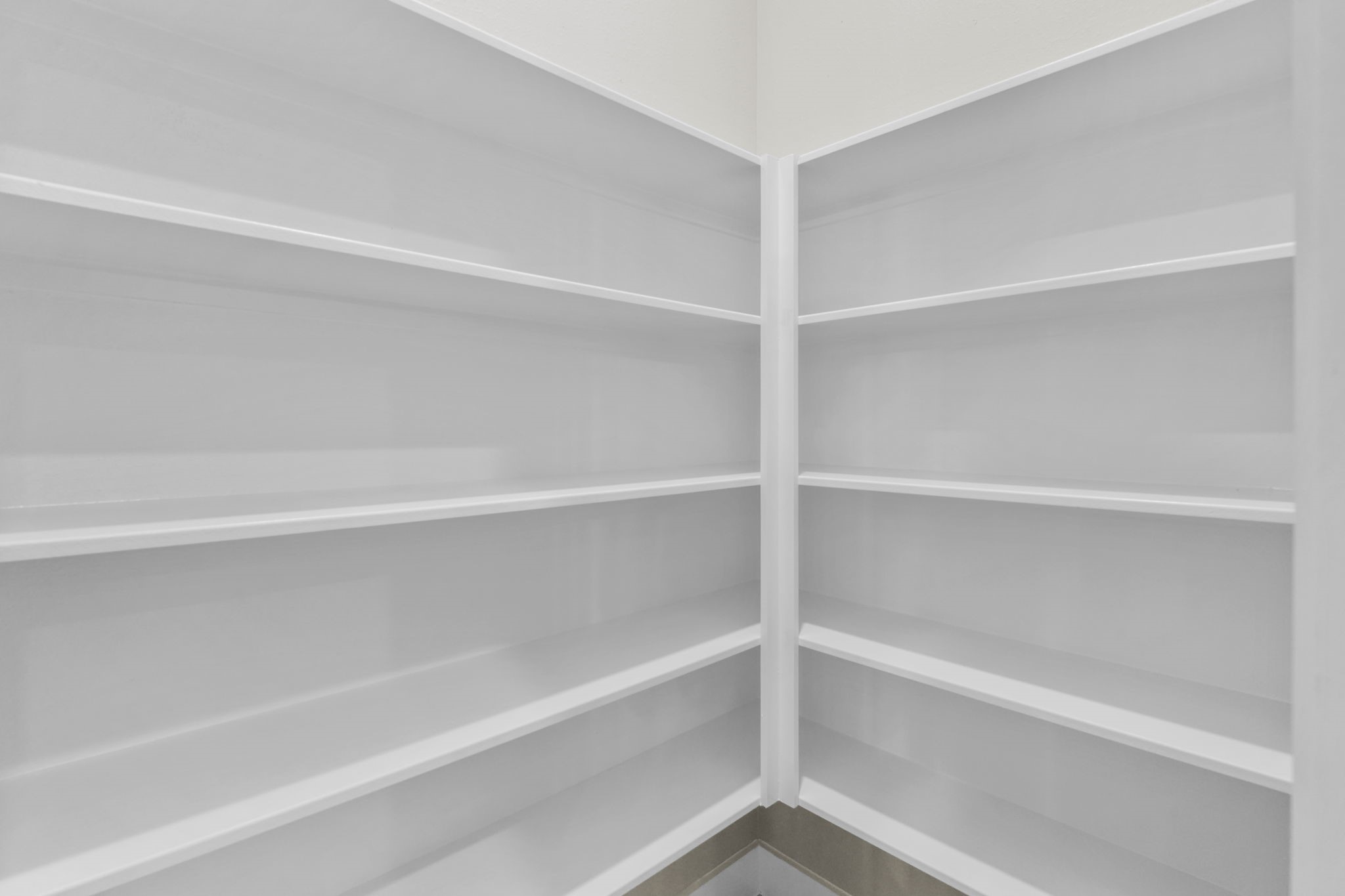 This dedicated walk-in pantry offers exceptional kitchen organization with multi-tiered, wrapped corner shelving.