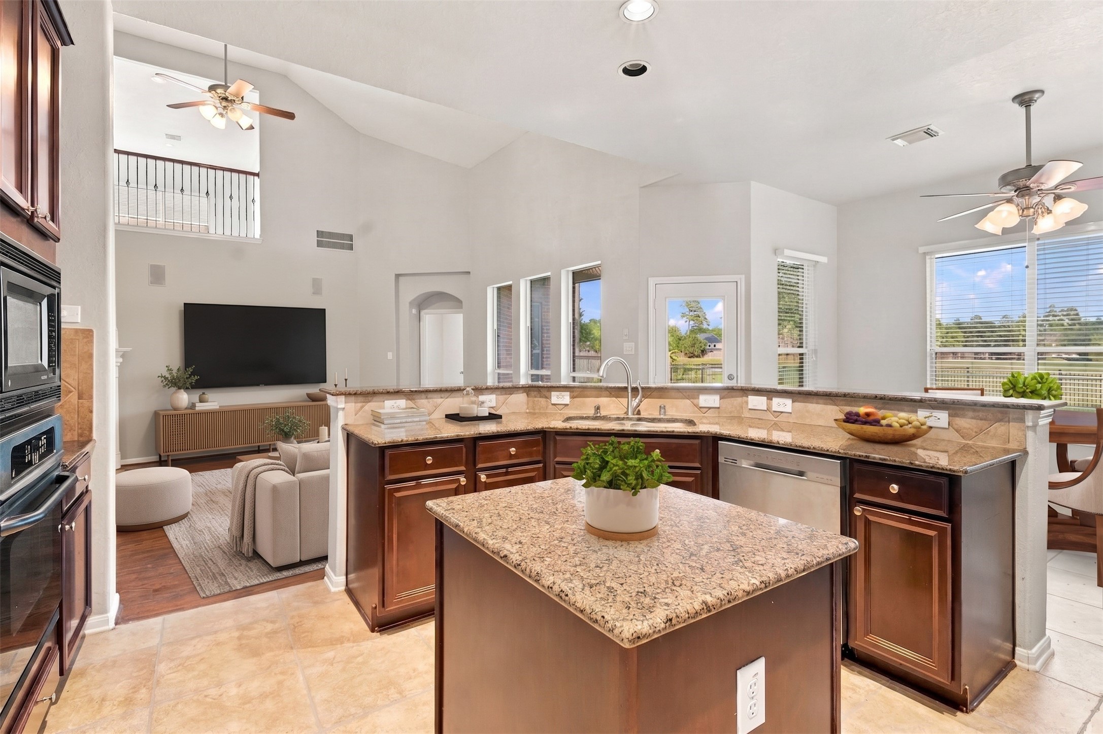 Virtually Staged:This functional open-concept kitchen features rich wood cabinetry, durable granite countertops, and a central island with built-in power outlets. The curved breakfast bar with an undermount sink offers a raised ledge overlooking the soaring living room.