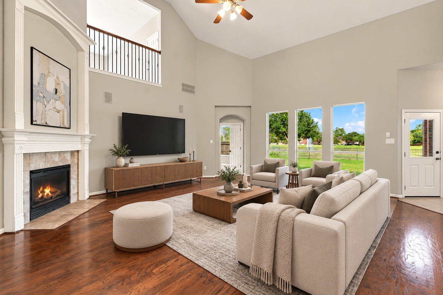 Virtually Staged: Designed with impressive proportions, this expansive family room offers exceptional vertical space and a seamless flow. Key features include a focal fireplace, overhead ceiling fan, and high-set wall windows that capture scenic outdoor views.