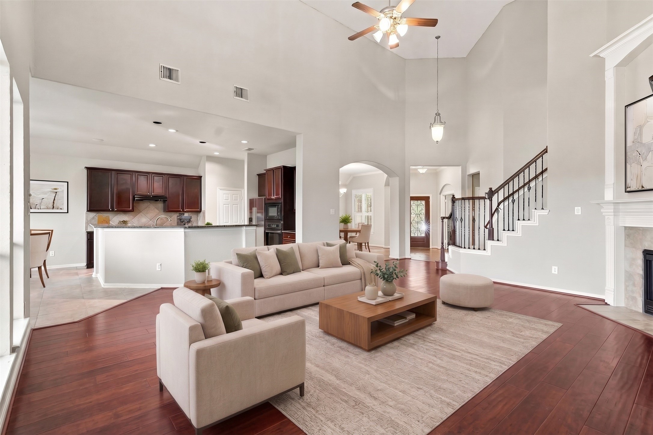 Virtually Staged: Key features include soaring vertical height, a ceiling fan fixture, detailed wall arches, and rich wood floors that extend across the primary gathering space.