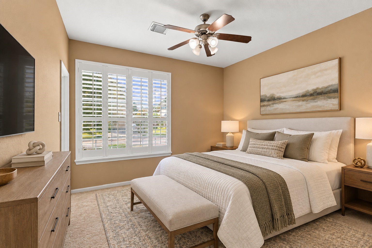 Virtually Staged: A bright and inviting secondary bedroom featuring warm neutral walls, soft carpeting, and a spacious layout with plenty of room for comfortable everyday living. A large window with plantation shutters fills the space with natural light, while the ceiling fan provides added comfort.