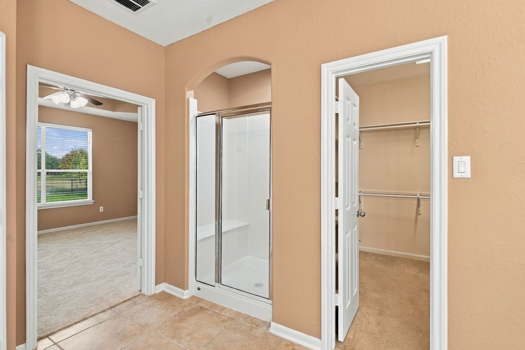 Designed for everyday convenience, this primary bathroom layout features a separate glass walk-in shower stall with integrated seating and easy-care tile flooring.