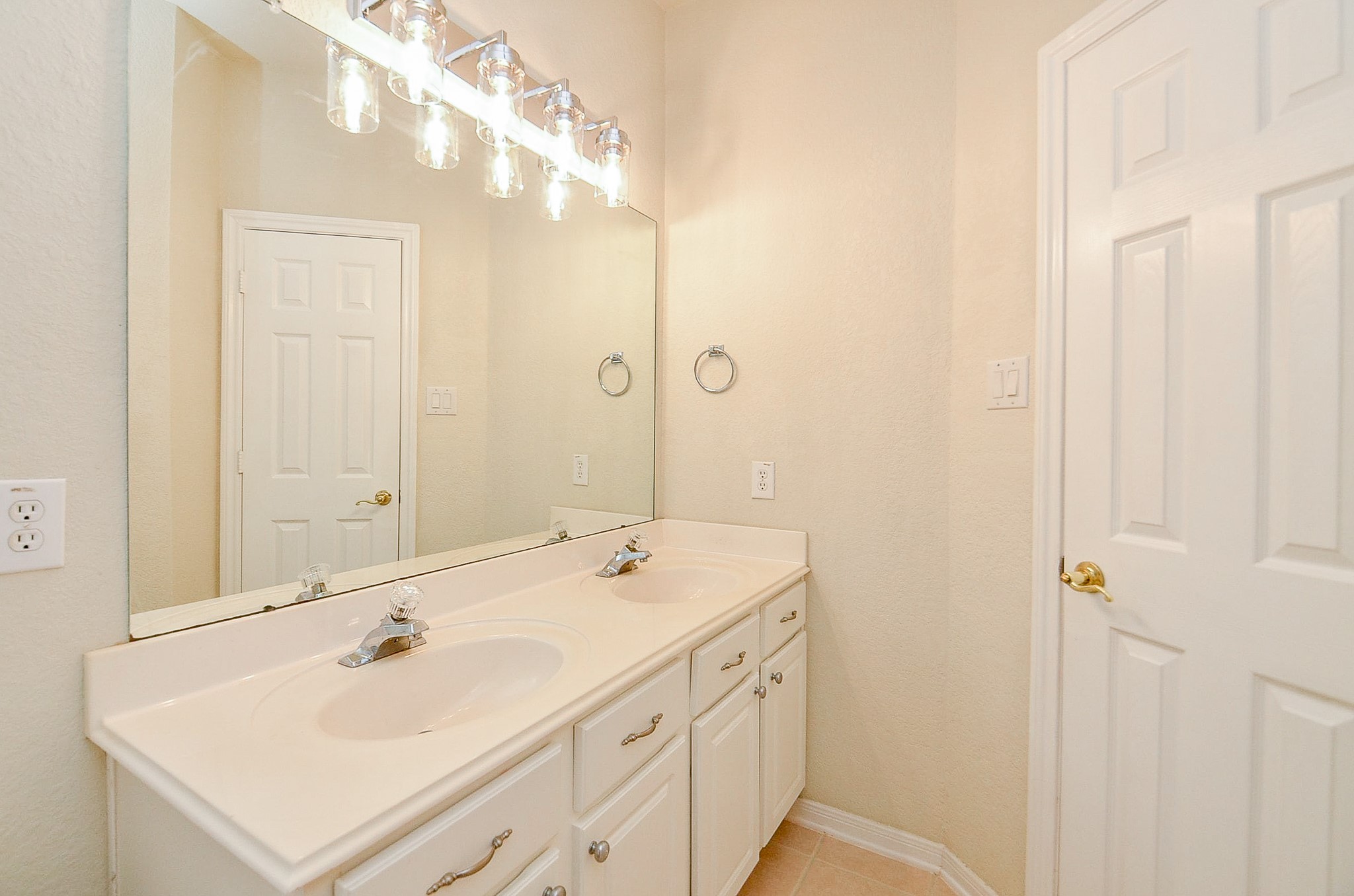 The secondary bath keeps busy mornings moving with a double-sink vanity, generous counter space and storage below. With three secondary bedrooms downstairs, having another full bath on this level is a practical bonus.