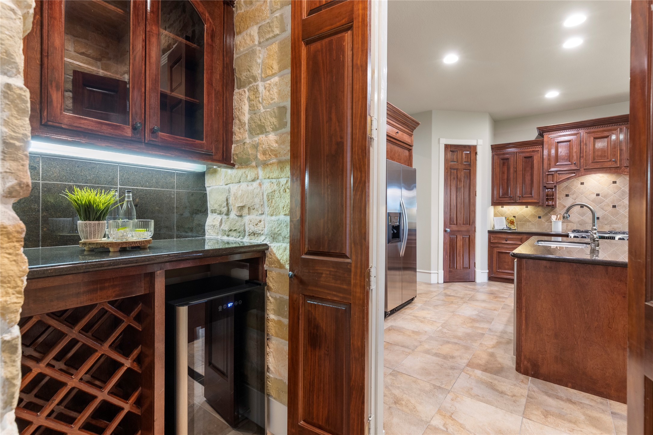 The wine pantry area includes rock accent walls and a 34 bottle wine refrigerator, adding a polished transition between kitchen and dining. It supports entertaining while giving the home another layer of custom detail.