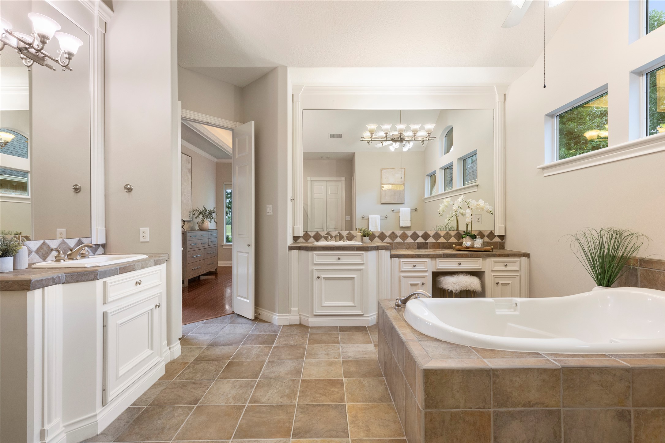 The primary bath includes separate vanities, a jetted tub, and generous natural light. Its layout offers comfort, space, and a classic suite experience.