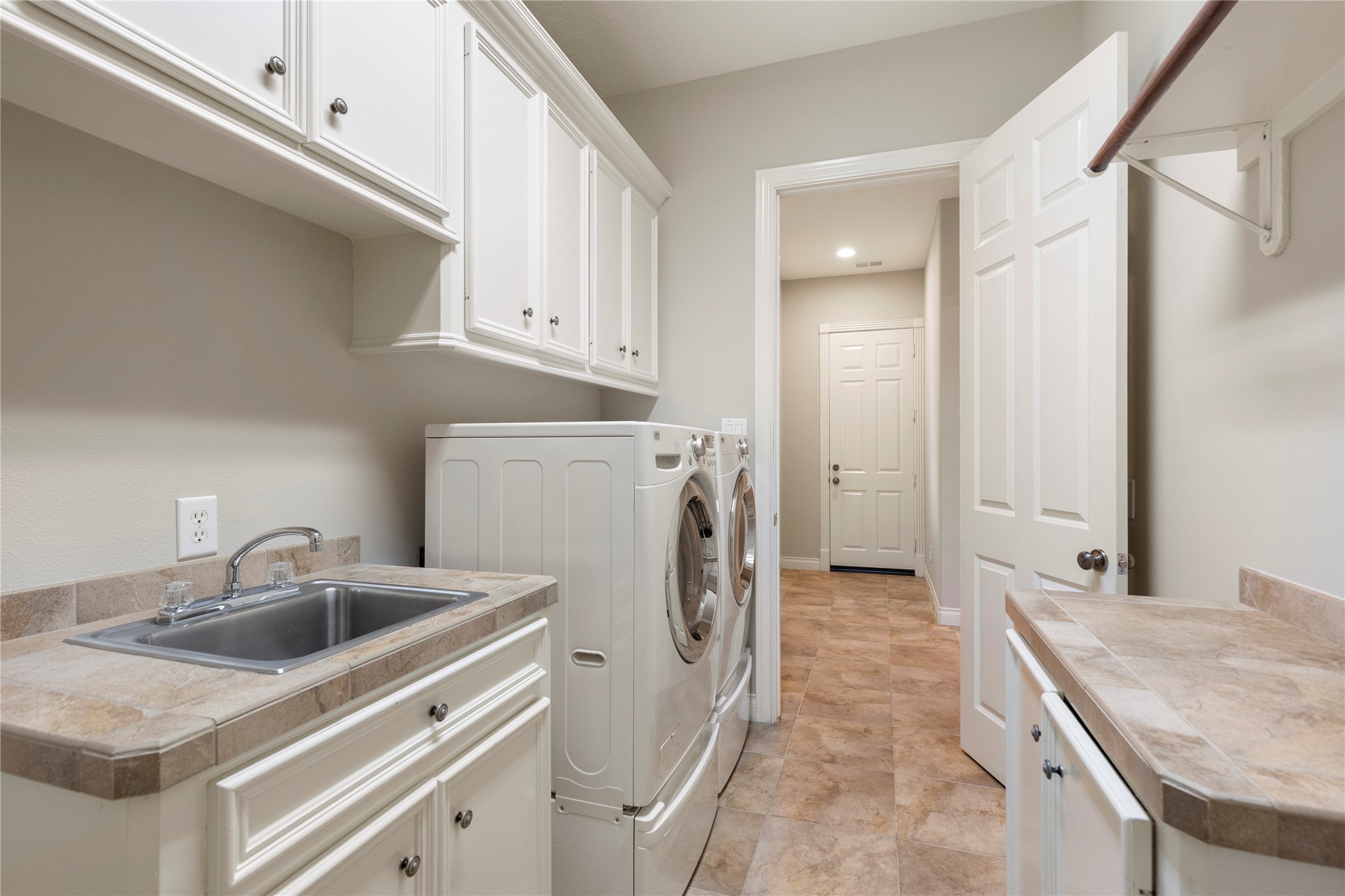 The utility room offers built in cabinetry, counter space, and a sink for added function. Its placement within the home keeps household tasks organized and accessible.