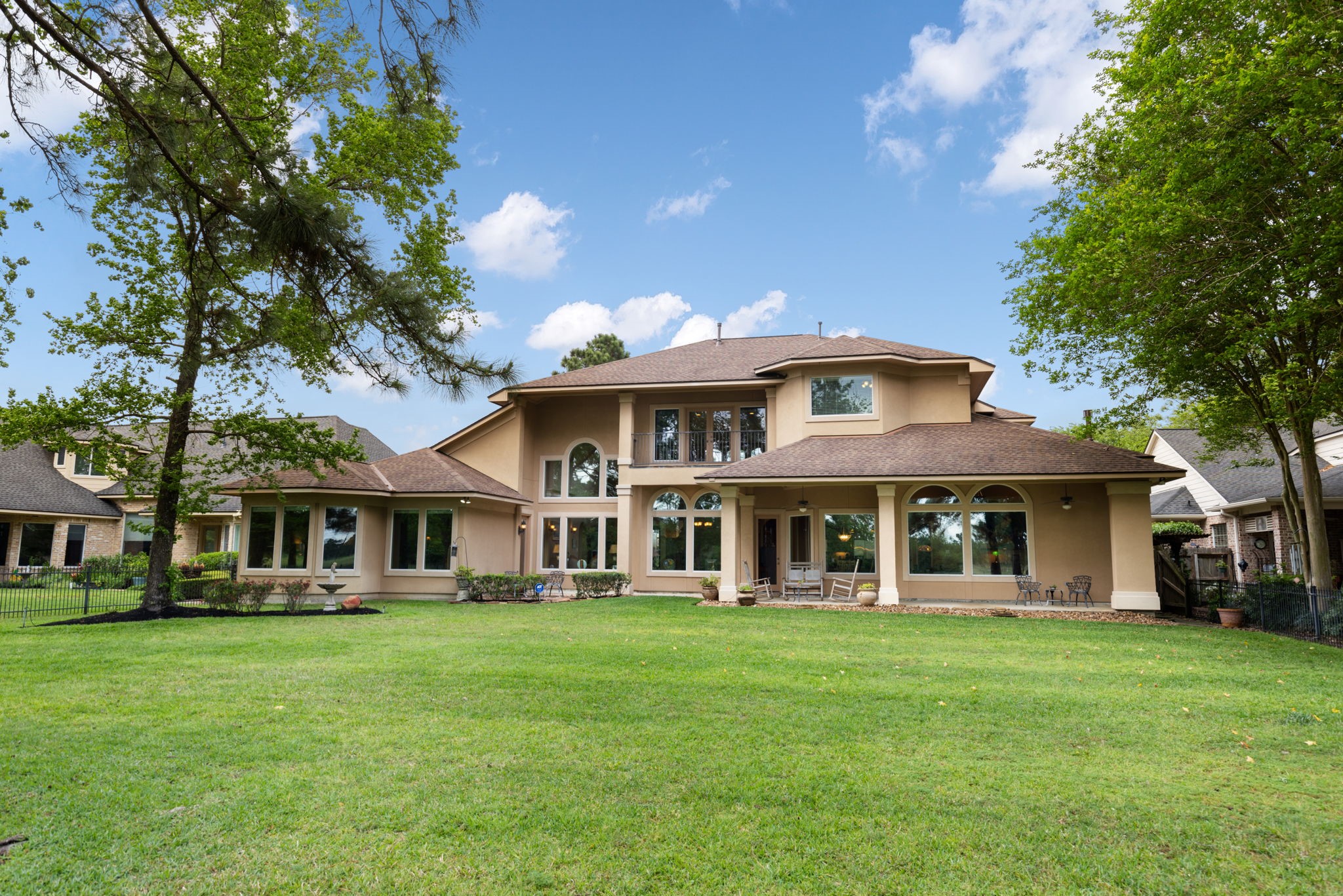 The rear elevation showcases the homes scale, covered outdoor living, and wide backyard opening to the golf course. The setting feels private, scenic, and rare for this price point.