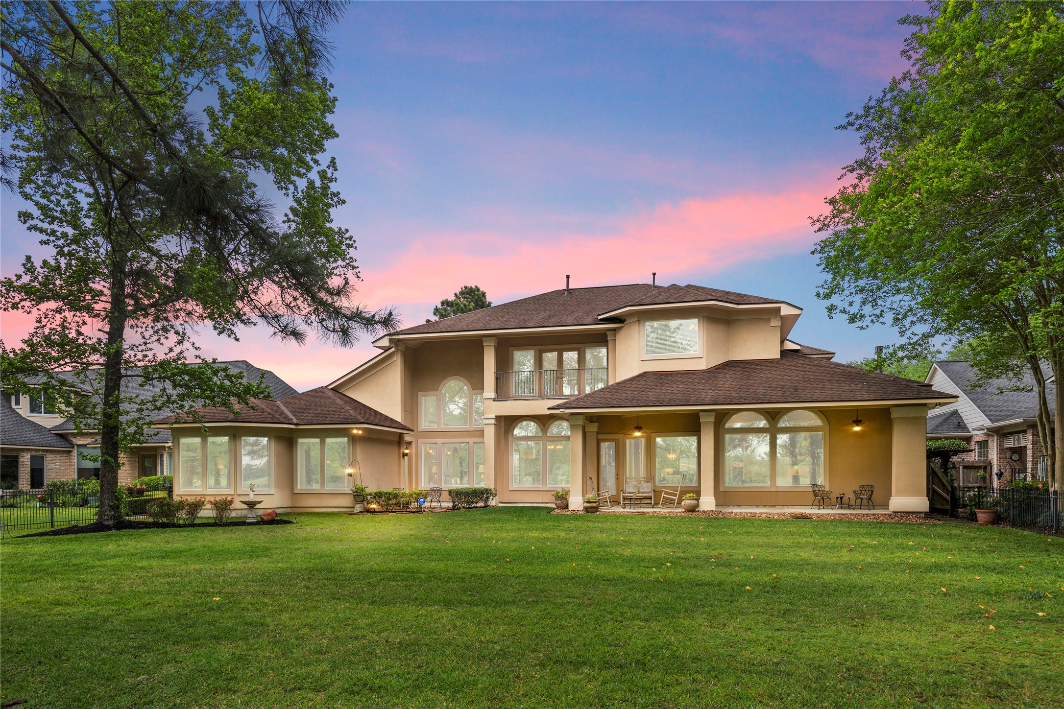 At twilight, the rear of the home glows against the golf course backdrop, creating a warm and memorable impression. The covered patio and large yard make the property feel inviting for evening gatherings.