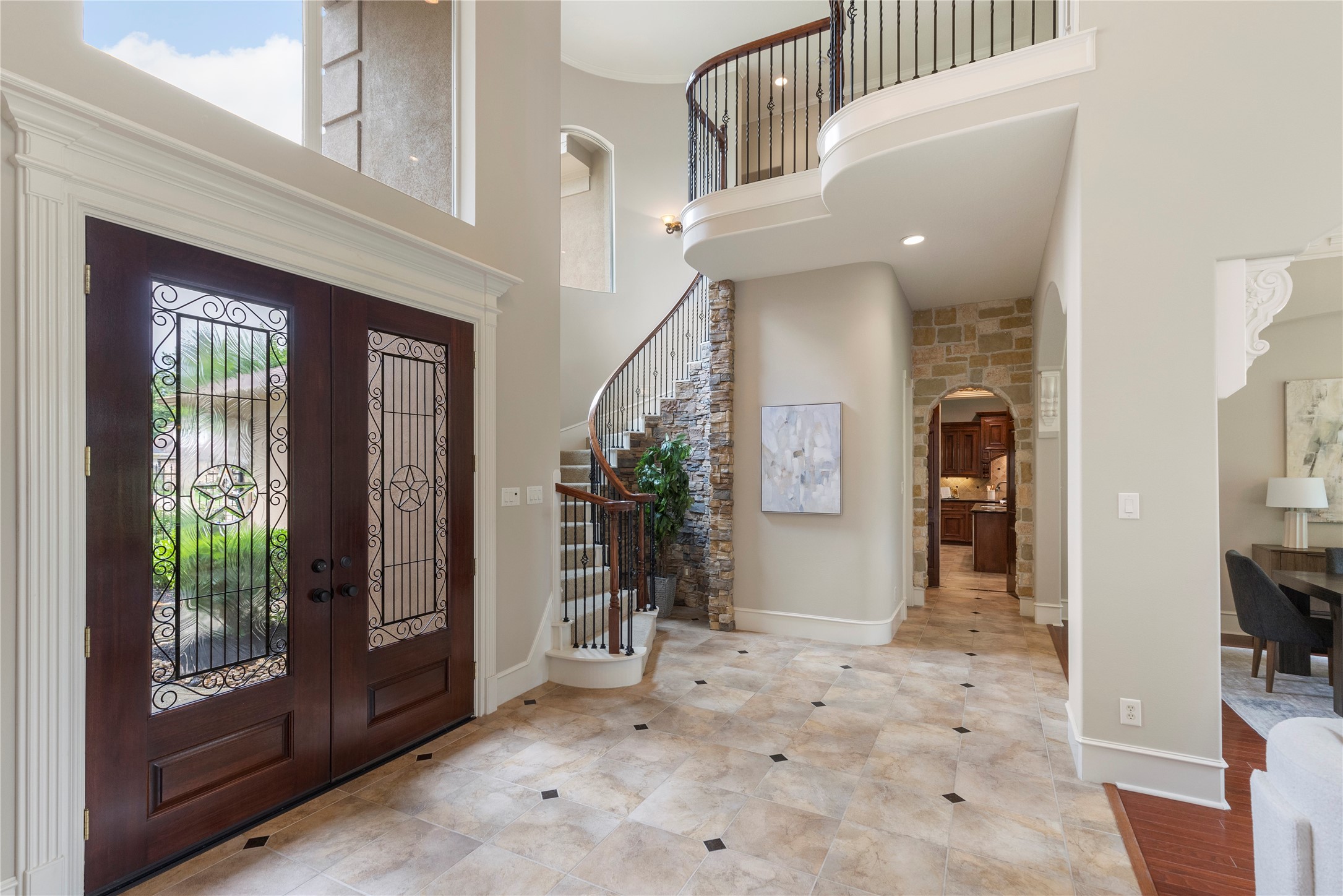 The curved staircase with wrought iron detail adds architectural presence to the center of the home. A rock accent wall enhances the custom character and gives the foyer a distinctive focal point. The curved staircase with wrought iron detail adds architectural presence to the center of the home. A rock accent wall enhances the custom character and gives the foyer a distinctive focal point.