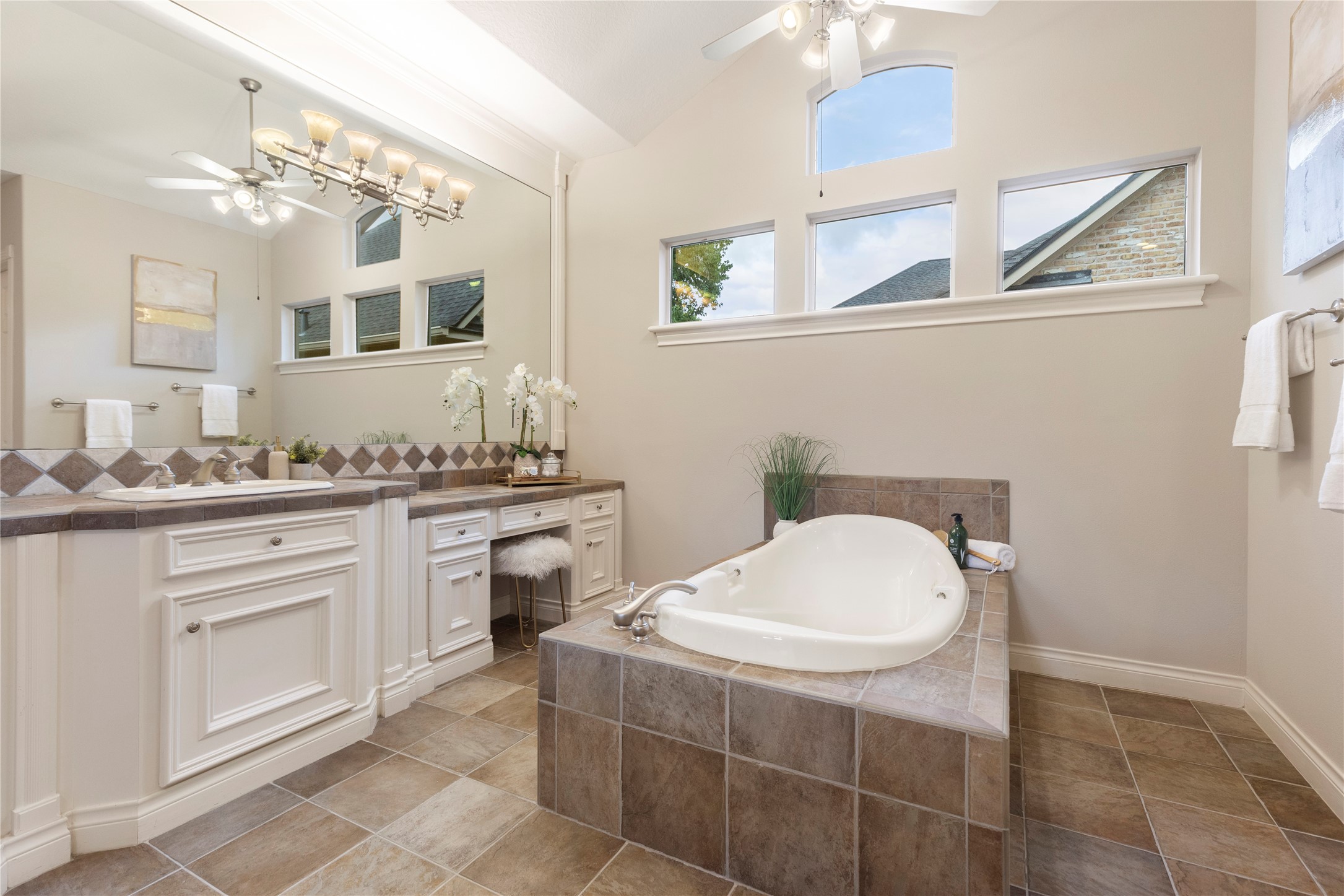The bathing area is framed by windows and a raised tub surround, creating a relaxing focal point within the suite. This space feels bright, spacious, and connected to the private setting outside.