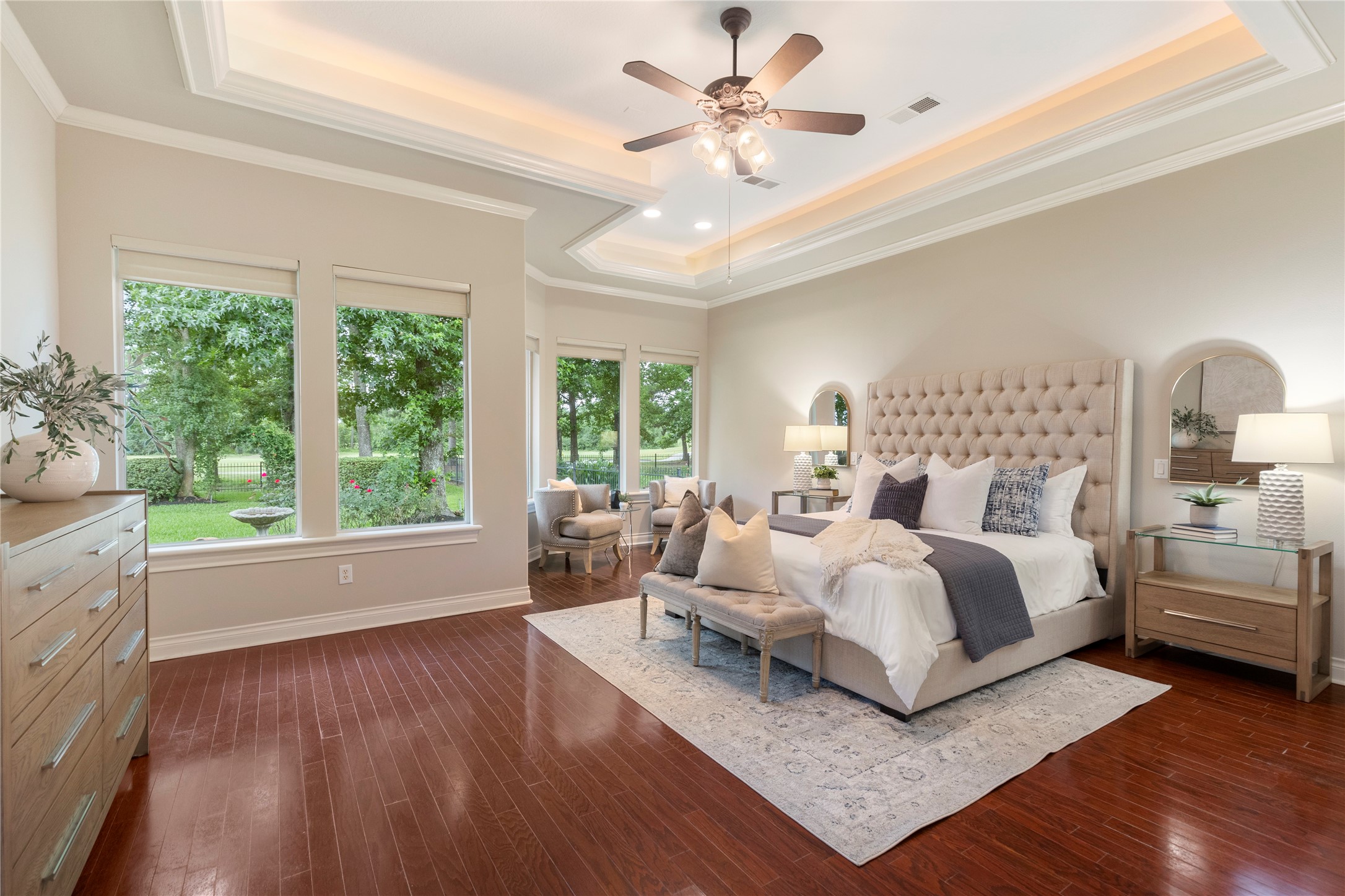 The first floor primary suite feels private and serene, positioned at the back of the home for quiet separation. Wood flooring and backyard views create a restful retreat with an elevated feel.