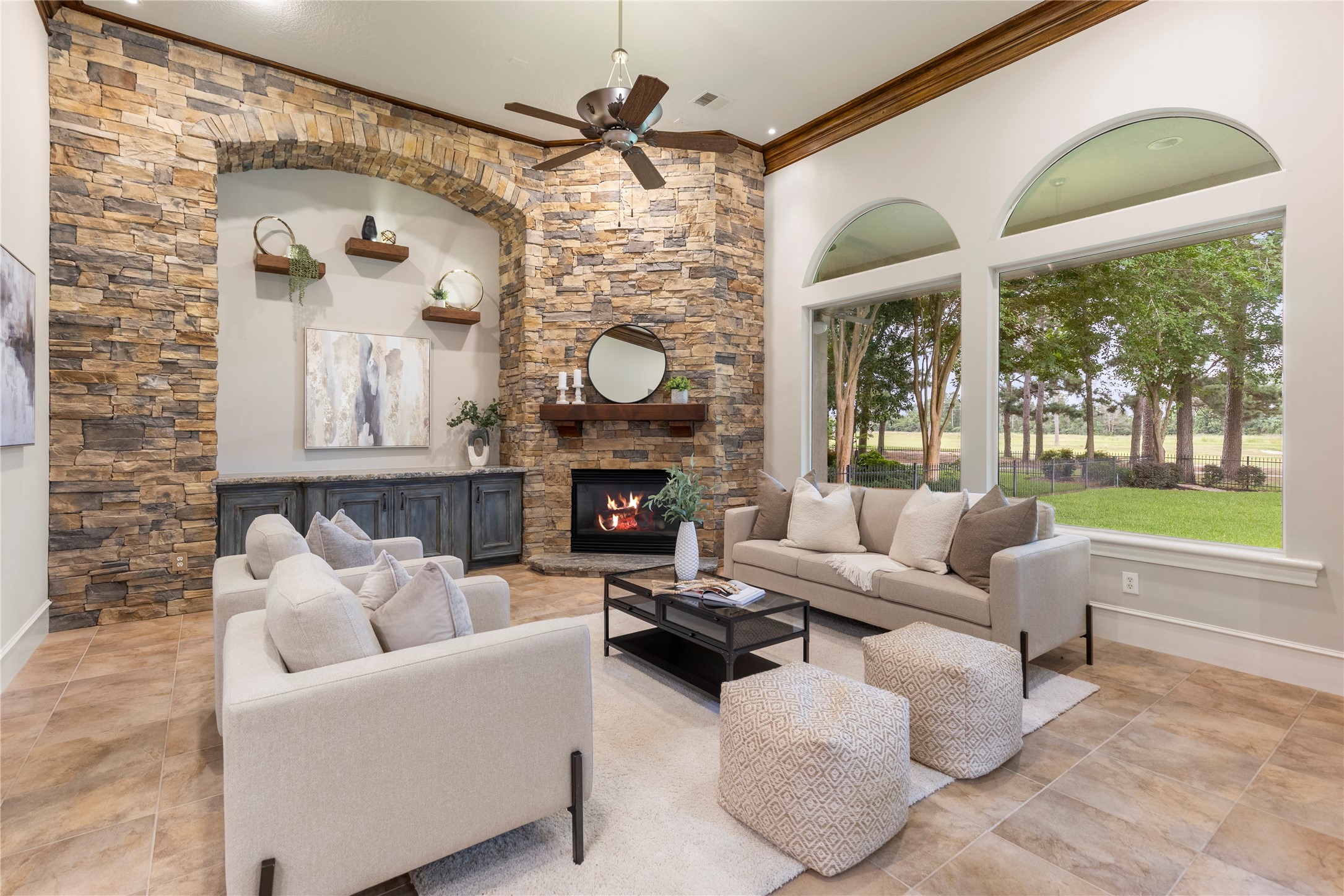 The den features a custom stone wall, quartzite hearth, lighted floating shelves, painted cabinetry, and a bespoke wood mantle. This remodel gives the room texture, warmth, and a strong architectural anchor.