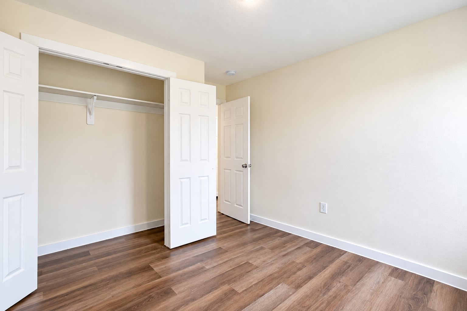 Bedroom with a large double door closet and wood style floors.